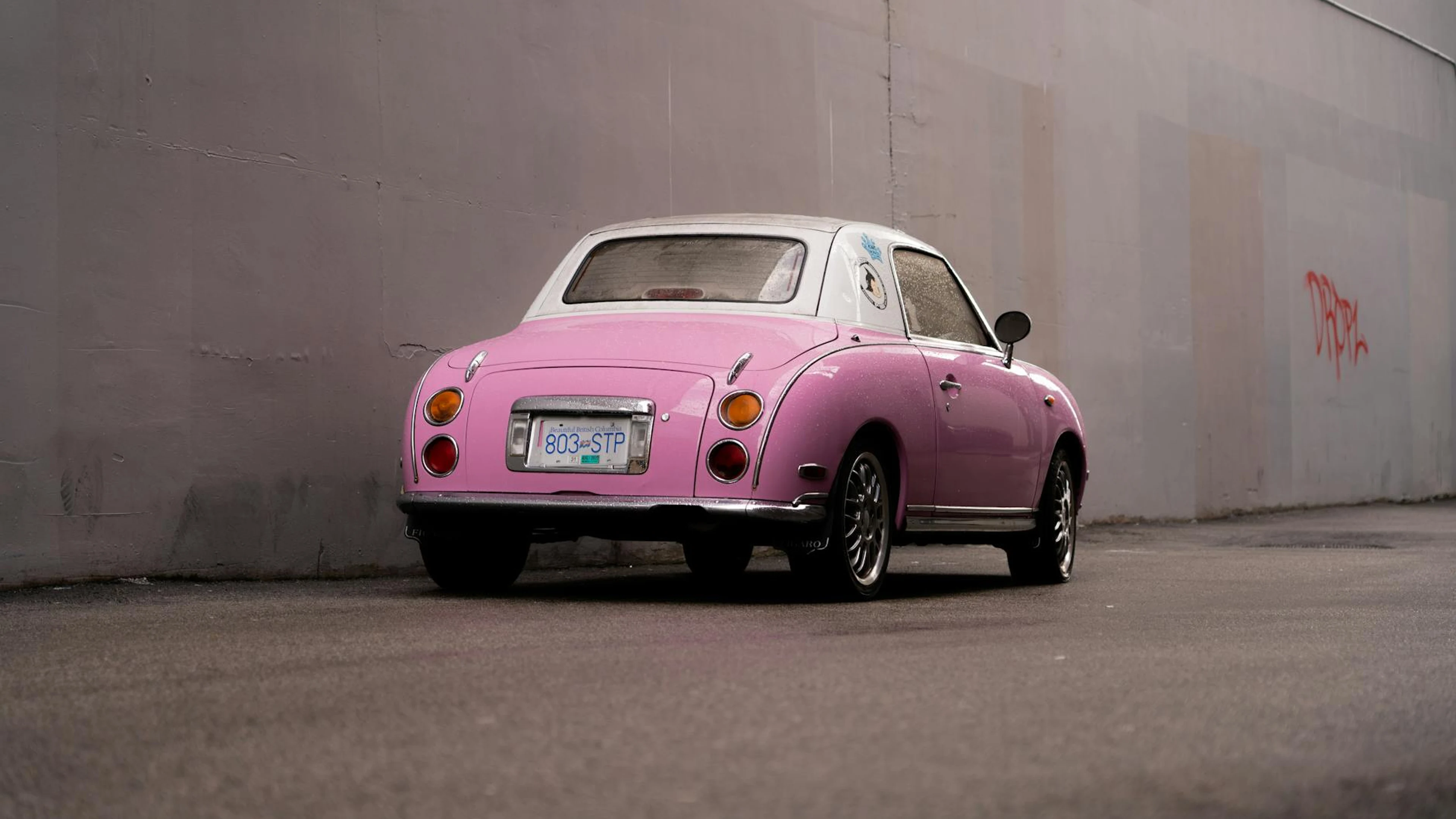 A vintage pink car parked against a city wall, showcasing retro style. - free 4K Ultra HD aesthetic wallpaper for desktop