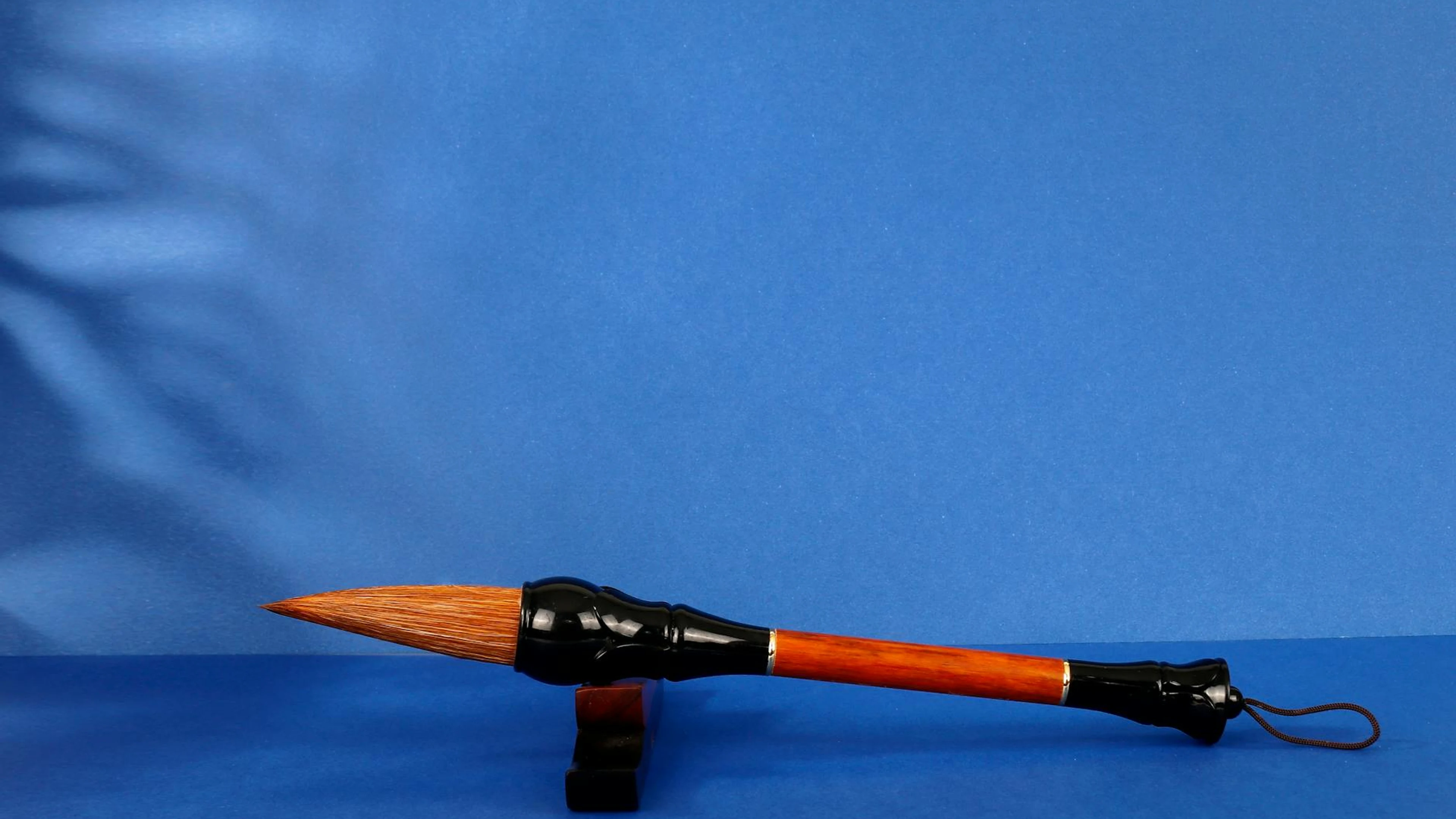 Close-up of a traditional calligraphy brush against a blue background with ample - free 4K Ultra HD anime wallpaper for desktop