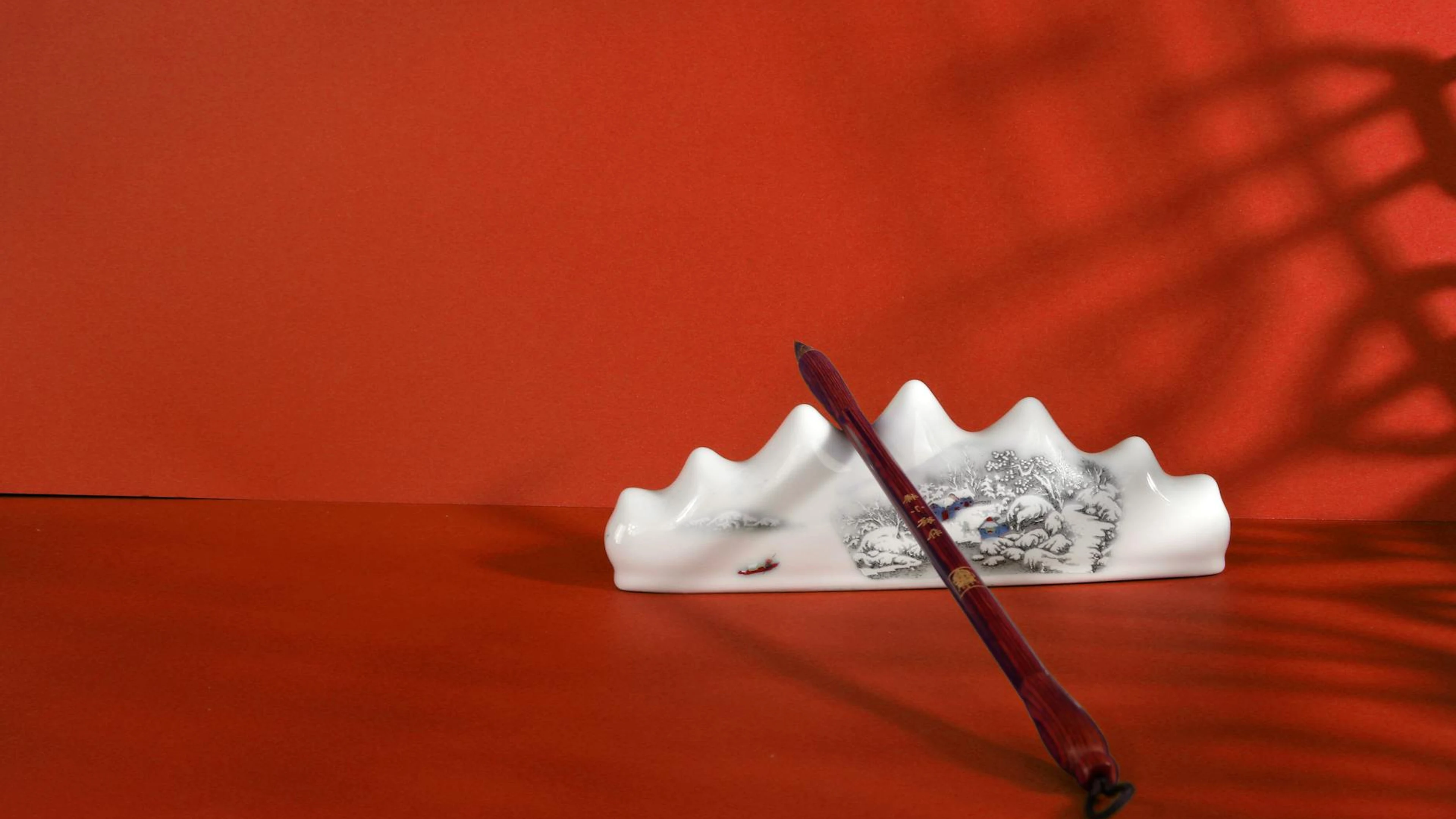 Elegant still life of an Asian ink brush with a ceramic holder against a red bac - free 4K Ultra HD anime wallpaper for desktop