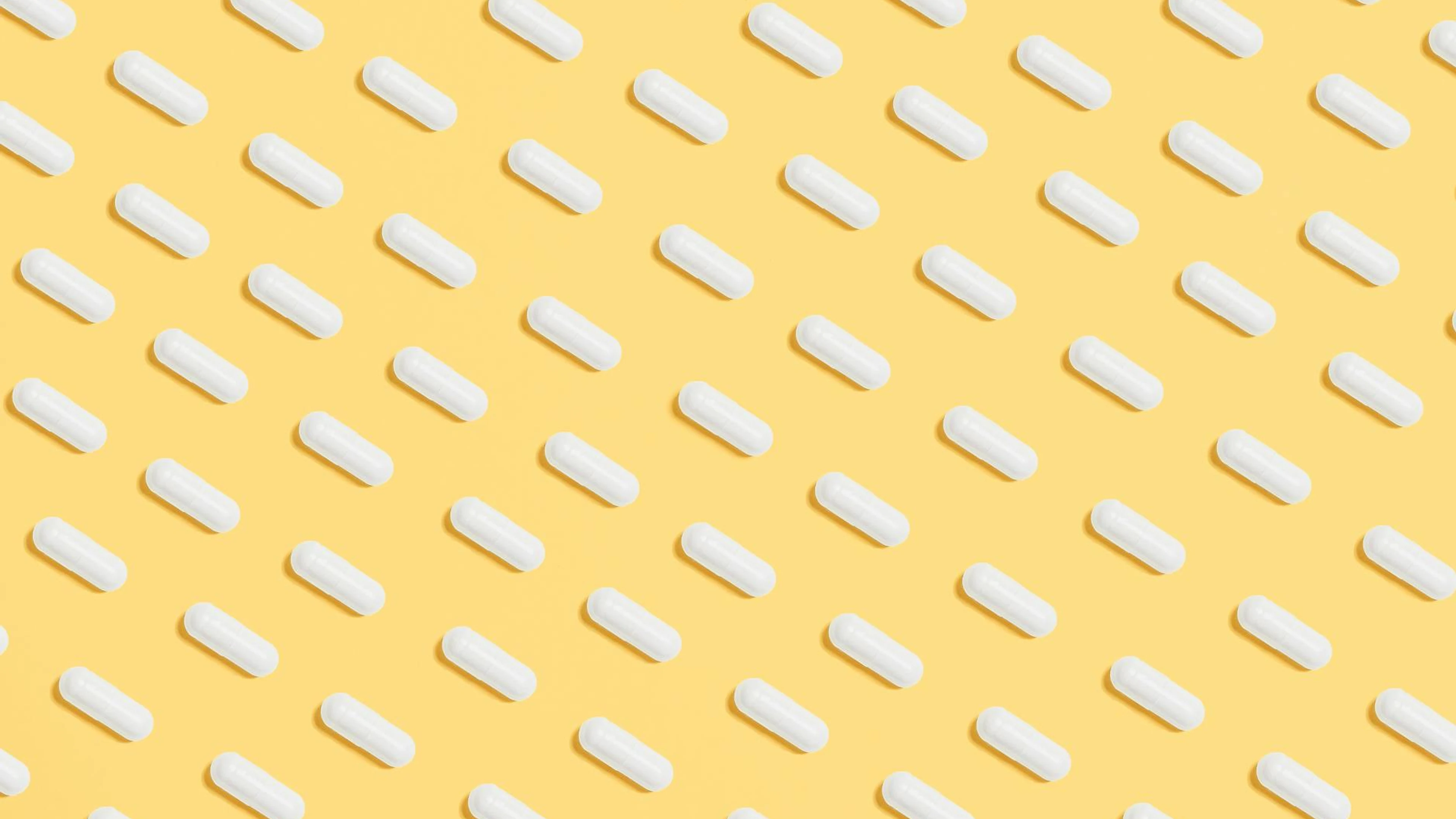 Pattern of white capsules on a bright yellow surface, symbolizing healthcare and - free 4K Ultra HD anime wallpaper for desktop