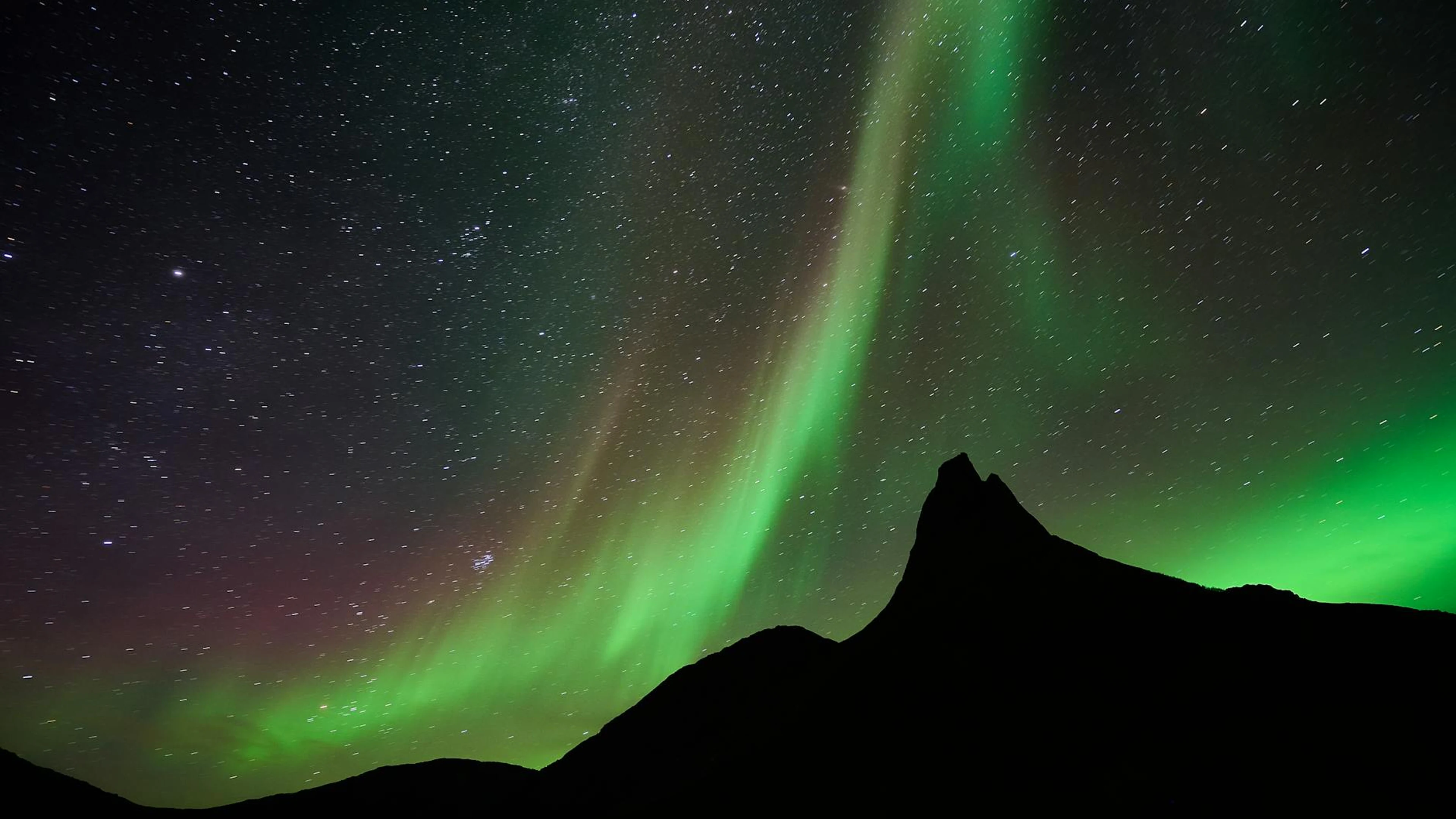 A mesmerizing display of northern lights dancing over a mountainous silhouette a - free 4K Ultra HD aurora wallpaper for desktop