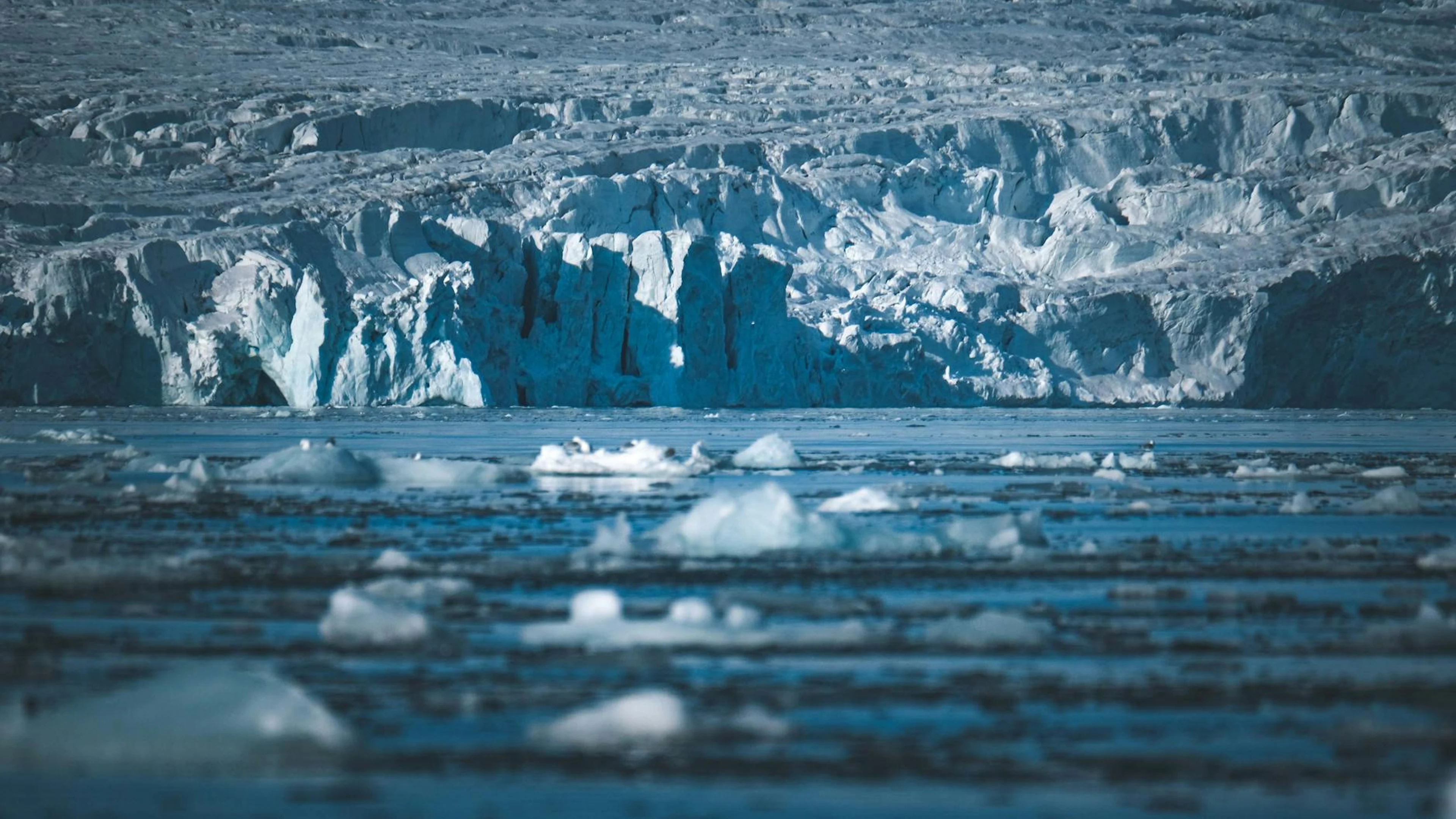A stunning view of Arctic icebergs floating in the sea against a massive glacier - free 4K Ultra HD aurora wallpaper for desktop