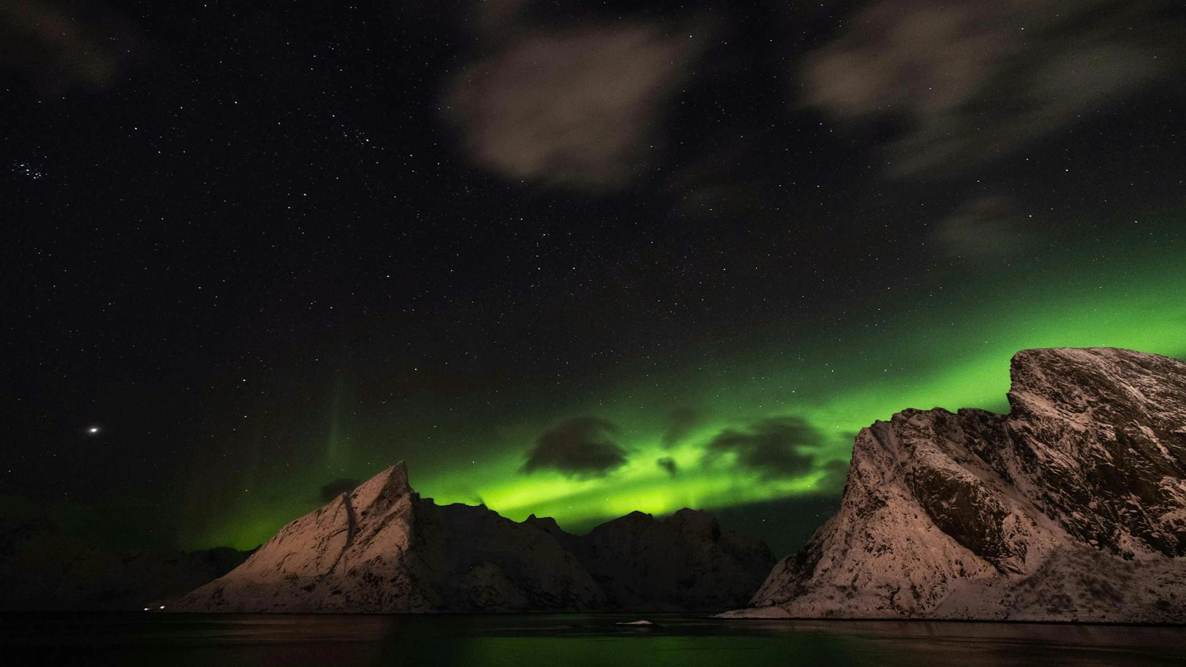 Breathtaking view of the Northern Lights above snow-covered mountains and a star - free 4K Ultra HD aurora wallpaper for desktop