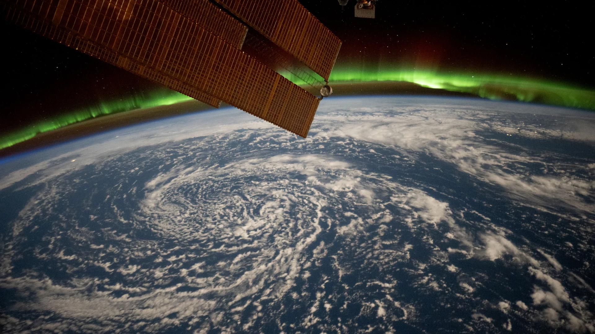 Clouds swirl over the Gulf of Alaska and underneath the aurora borealis - free hd aurora wallpaper for desktop