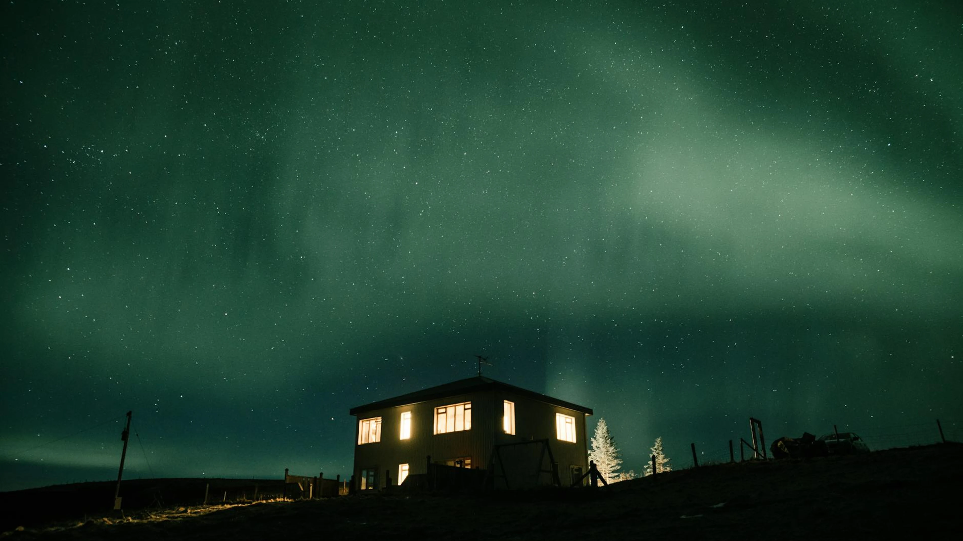 House beneath stunning night sky featuring northern lights. Starry night with an - free 4K Ultra HD aurora wallpaper for desktop