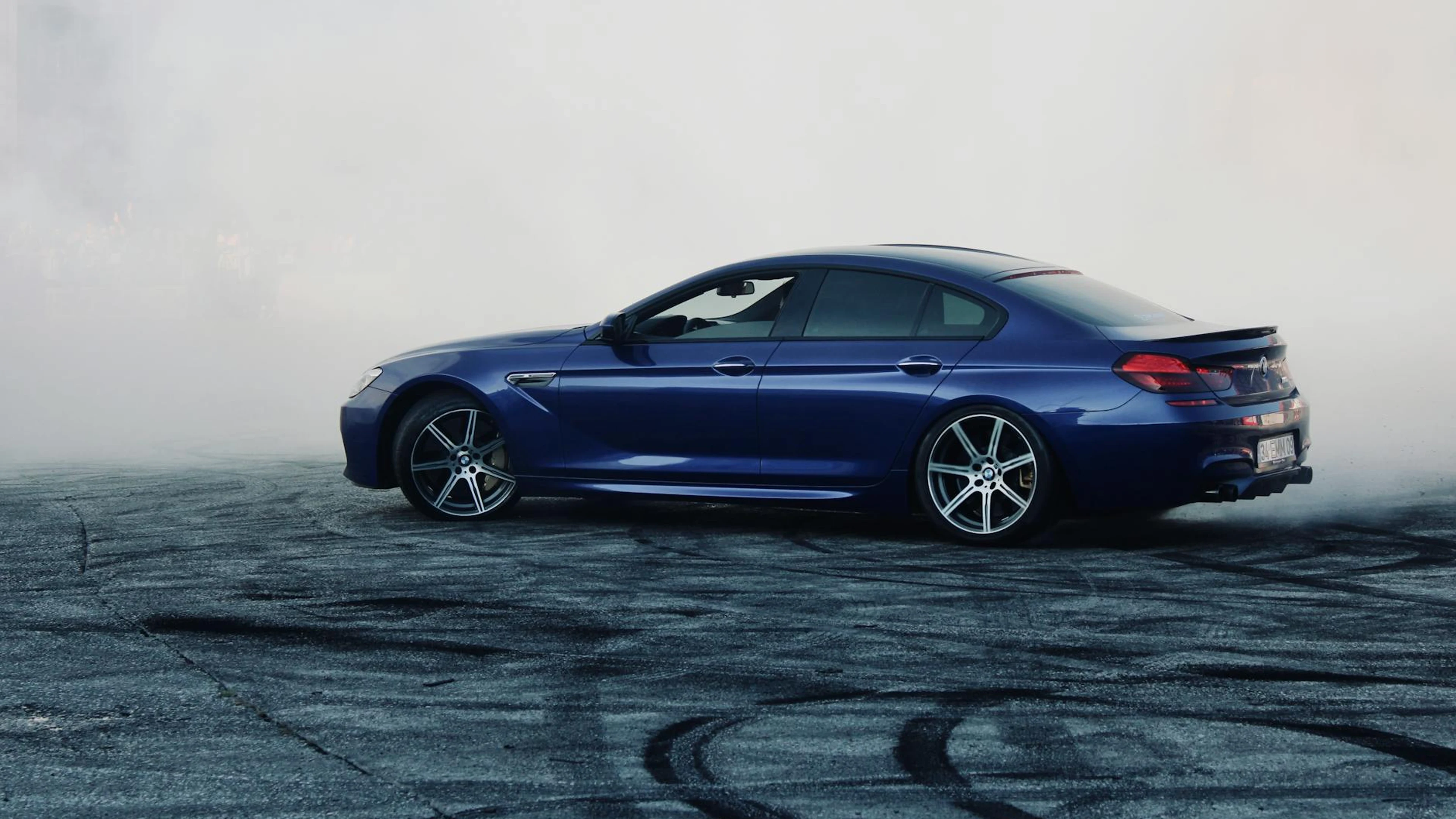 A sleek blue car performing a dramatic drift on an open asphalt area in Turkey. - free 4K Ultra HD cars wallpaper for desktop