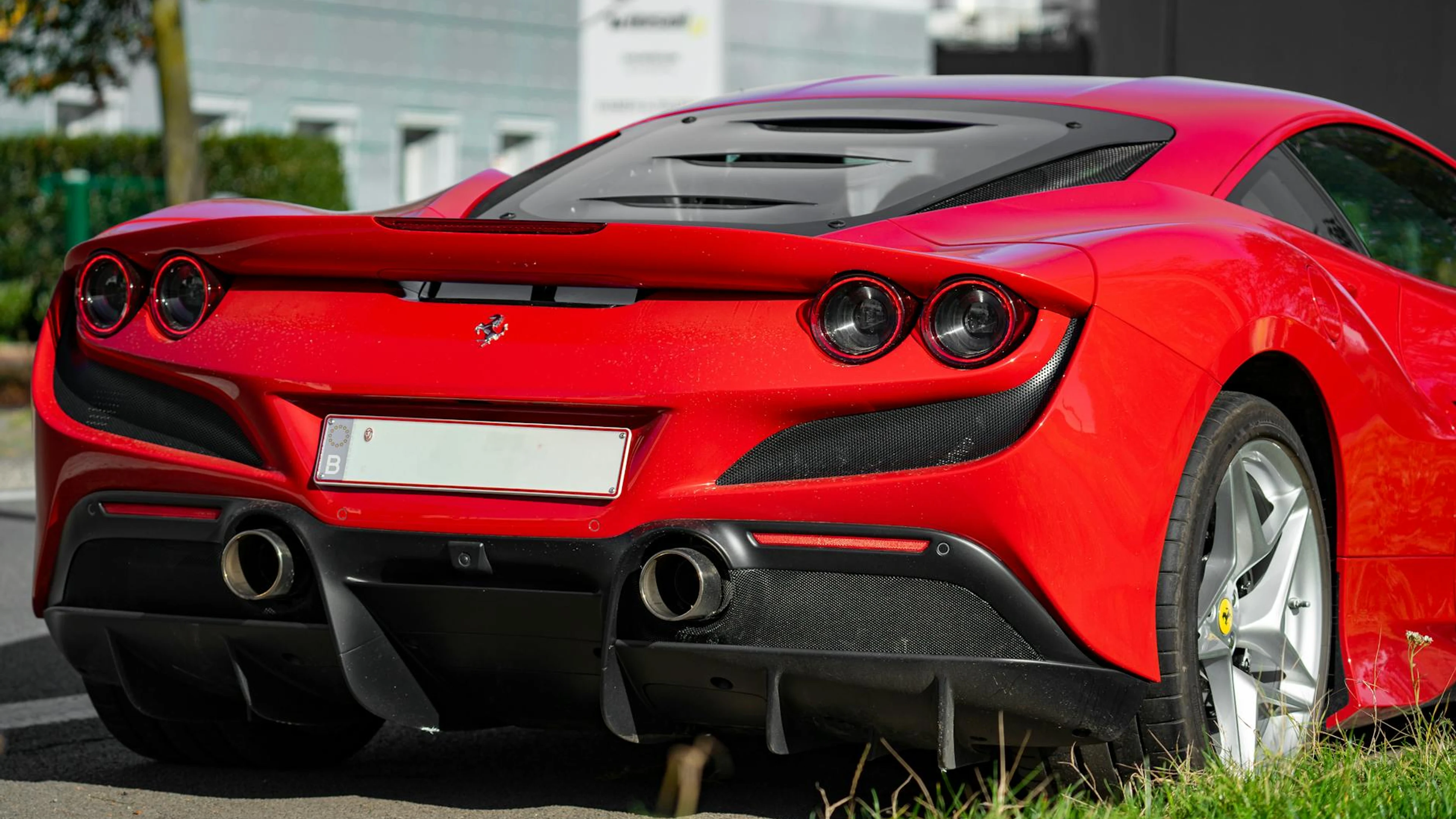 A striking red sports car parked on an urban street, showcasing luxury design. - free 4K Ultra HD cars wallpaper for desktop