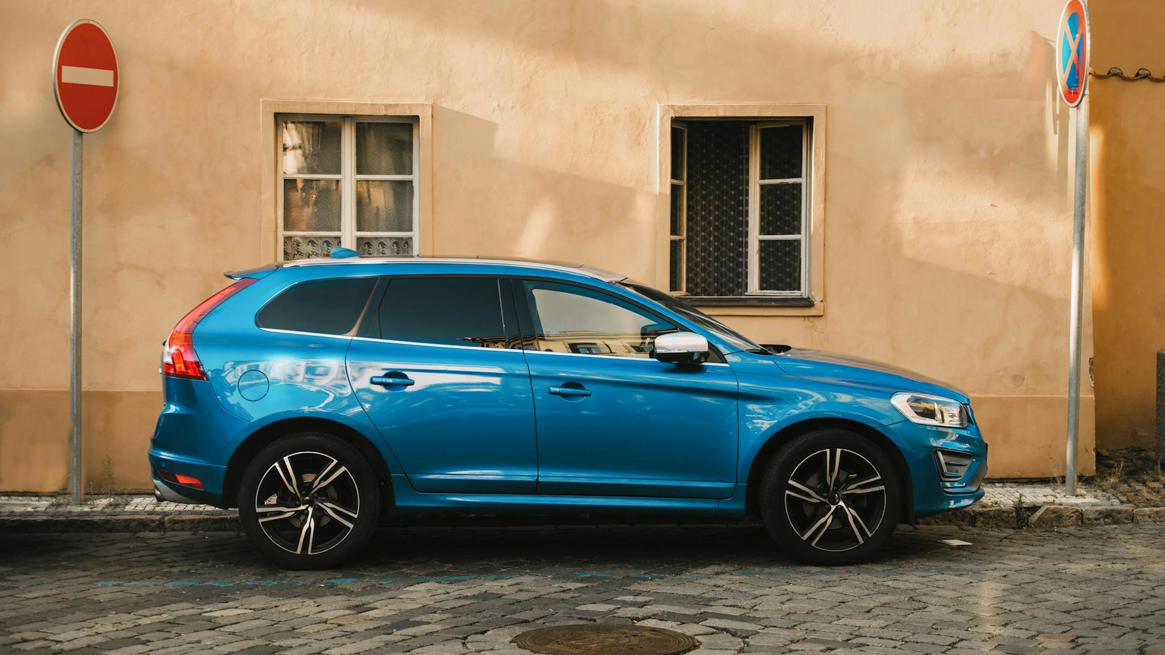 Blue SUV parked by a historic building in Prague, showcasing street signs and ci - free 4K Ultra HD cars wallpaper for desktop