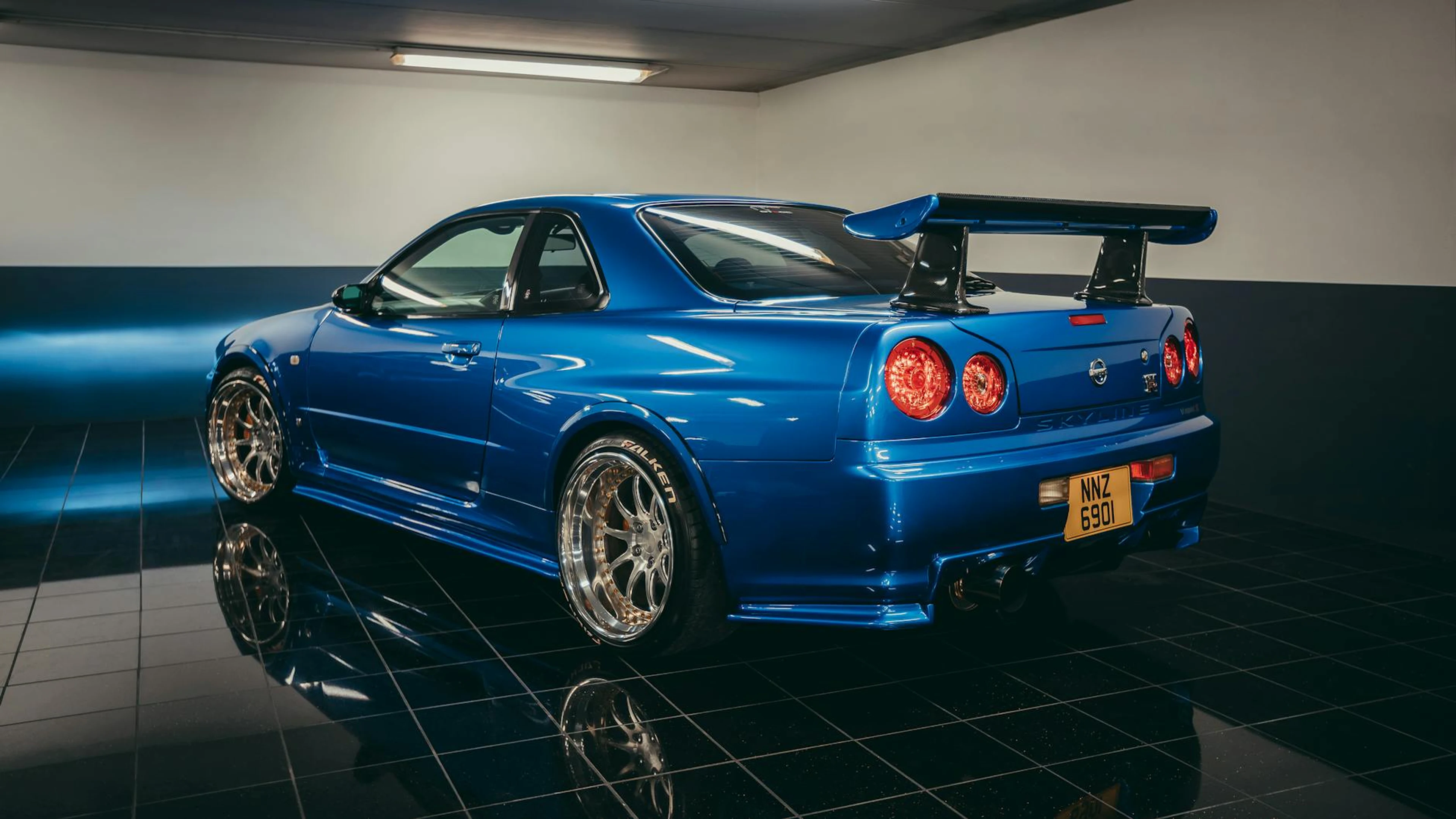 Dynamic shot of a blue Nissan Skyline GTR parked in a sleek indoor garage. - free 4K Ultra HD cars wallpaper for desktop