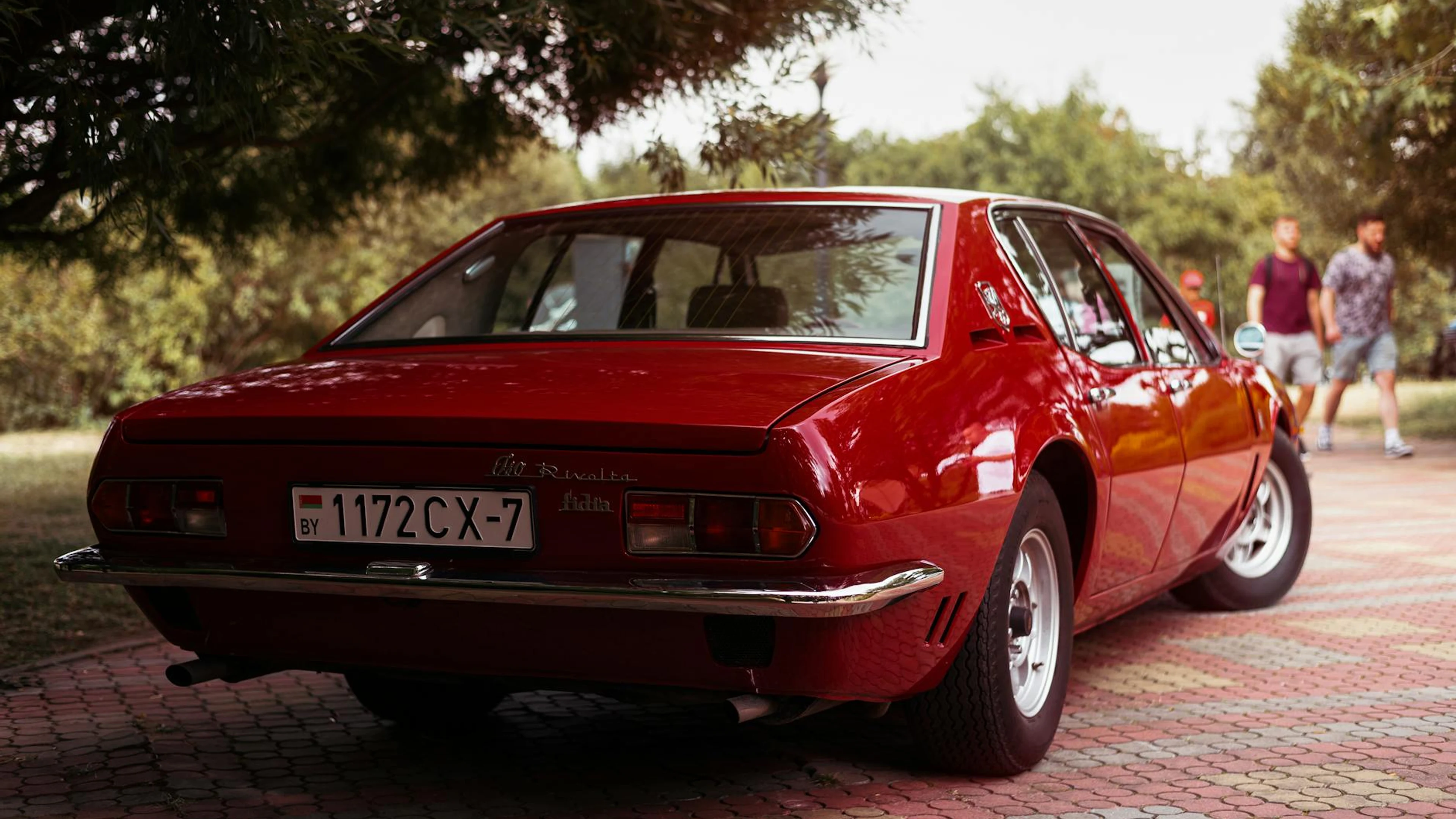 Rear view of a classic red Iso Rivolta sedan parked outdoors on a tiled path. - free 4K Ultra HD cars wallpaper for desktop
