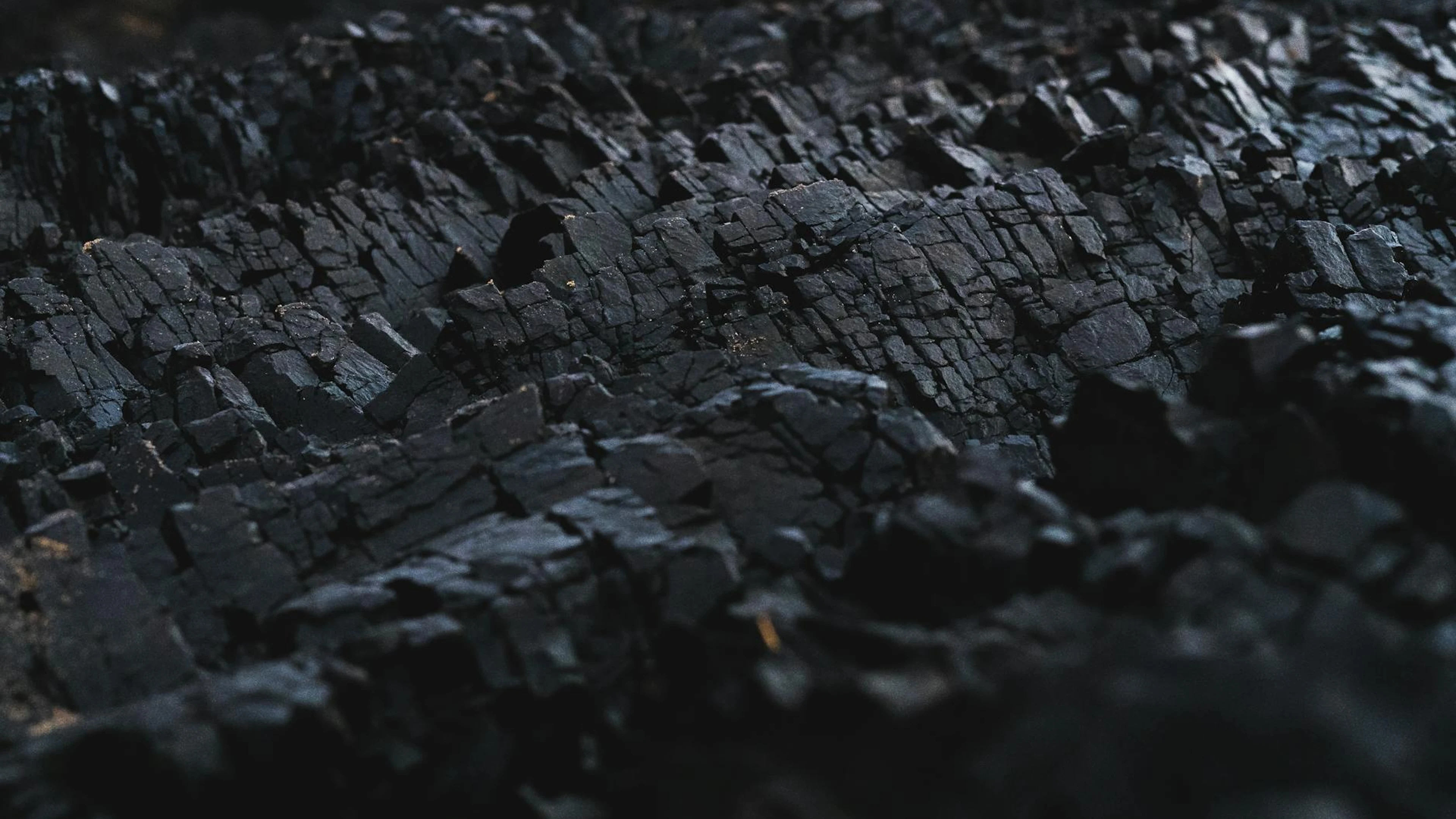 A detailed close-up of dark charcoal texture, showcasing its rough and jagged su - free 4K Ultra HD dark wallpaper for desktop