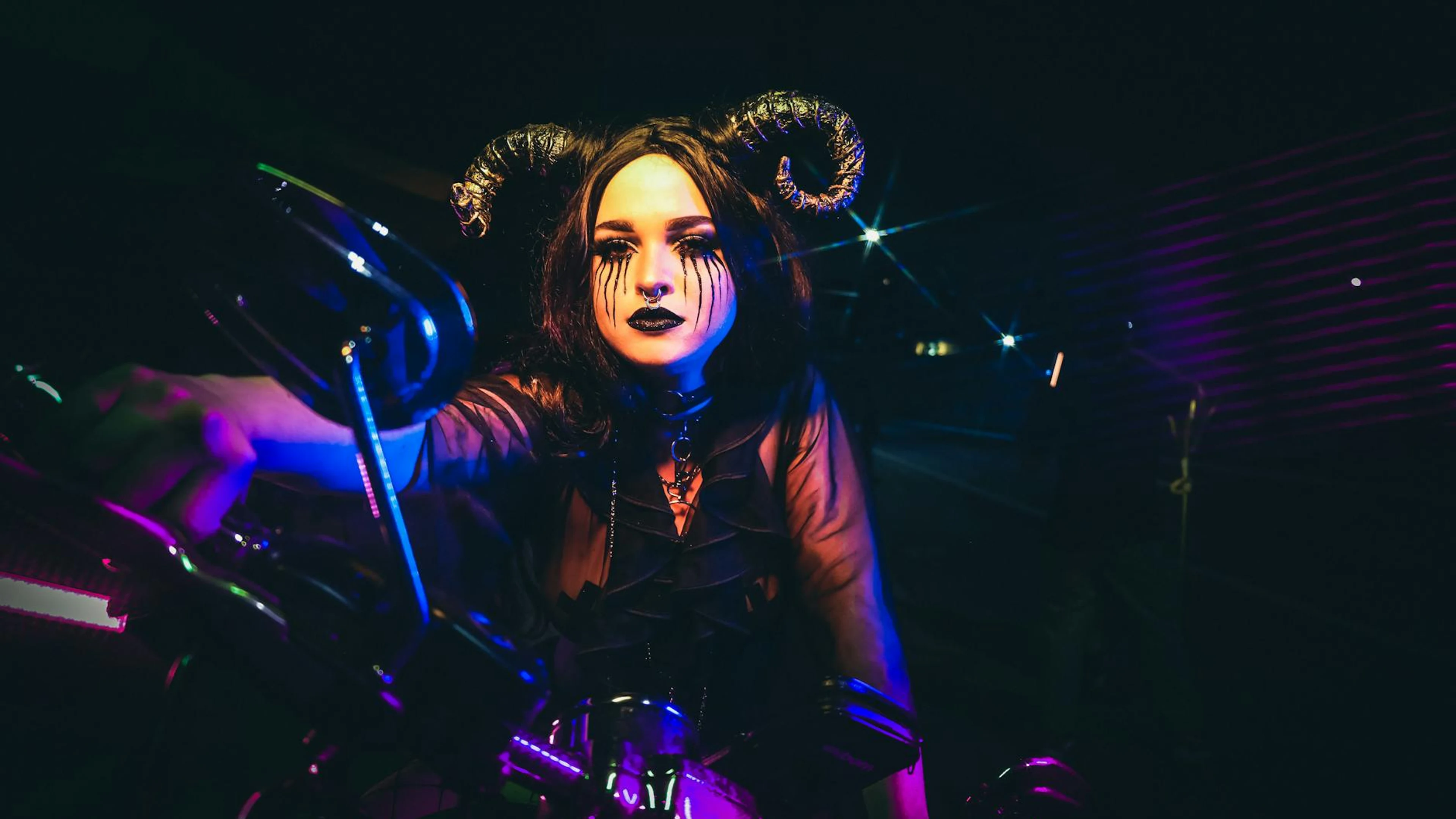 A woman with dramatic makeup and horns on a motorcycle in a vivid night setting, - free 4K Ultra HD dark wallpaper for desktop