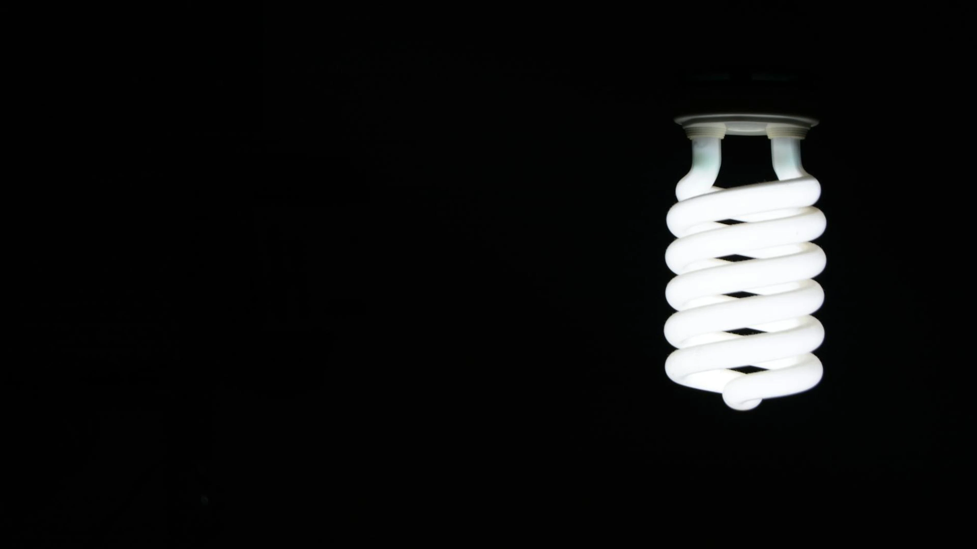 Bright spiral LED lightbulb against black background, artistic minimalism. - free 4K Ultra HD dark wallpaper for desktop