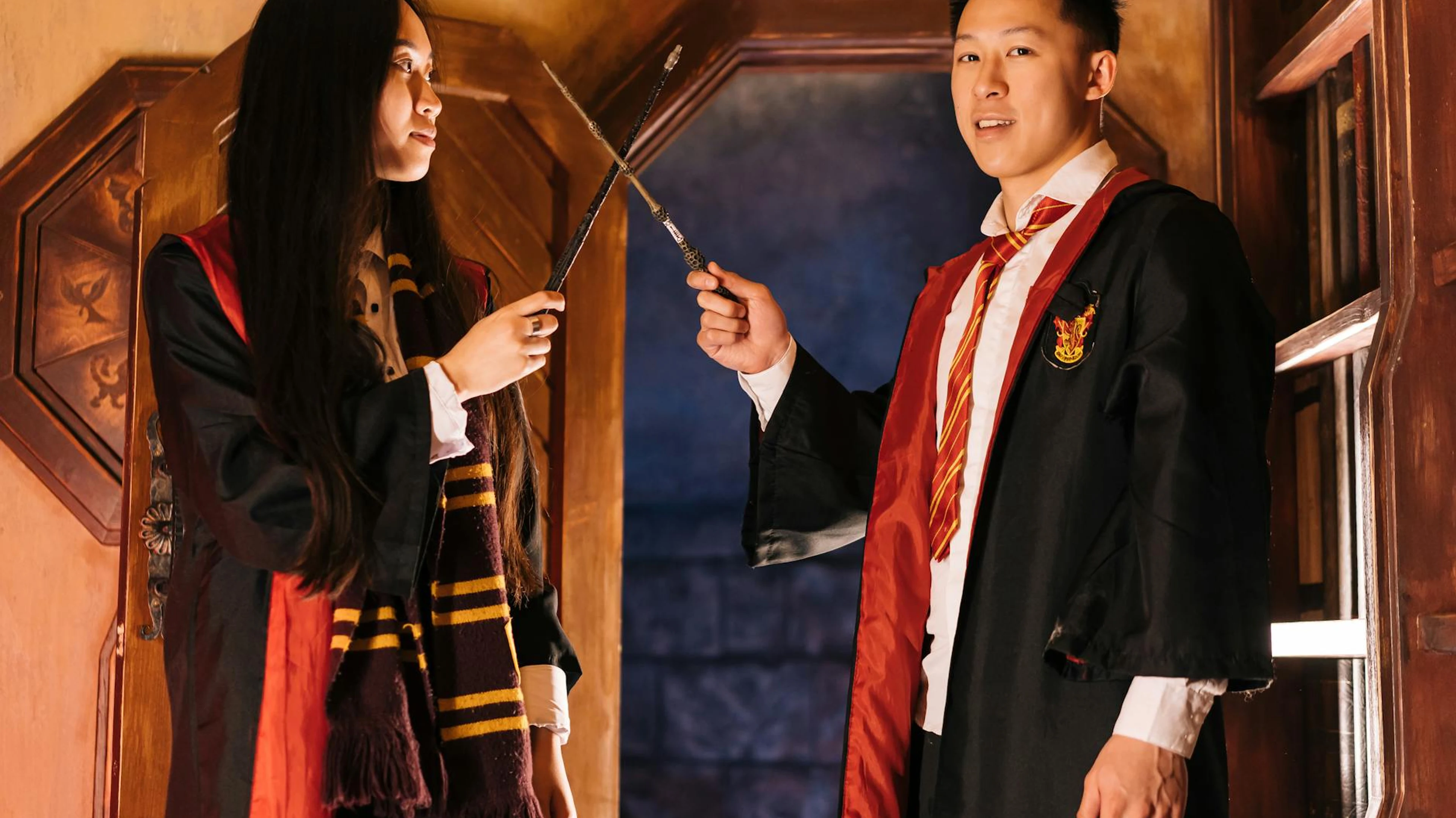 Two young adults dressed as wizards holding wands in a magical setting. - free 4K Ultra HD fantasy wallpaper for desktop
