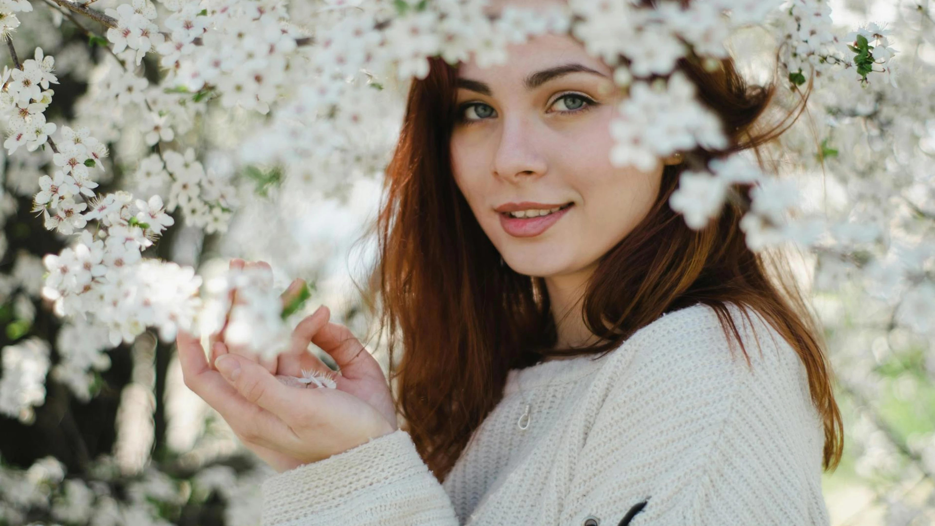Young woman in spring, smiling gently, surrounded by blossom flowers. - free 4K Ultra HD flowers wallpaper for desktop