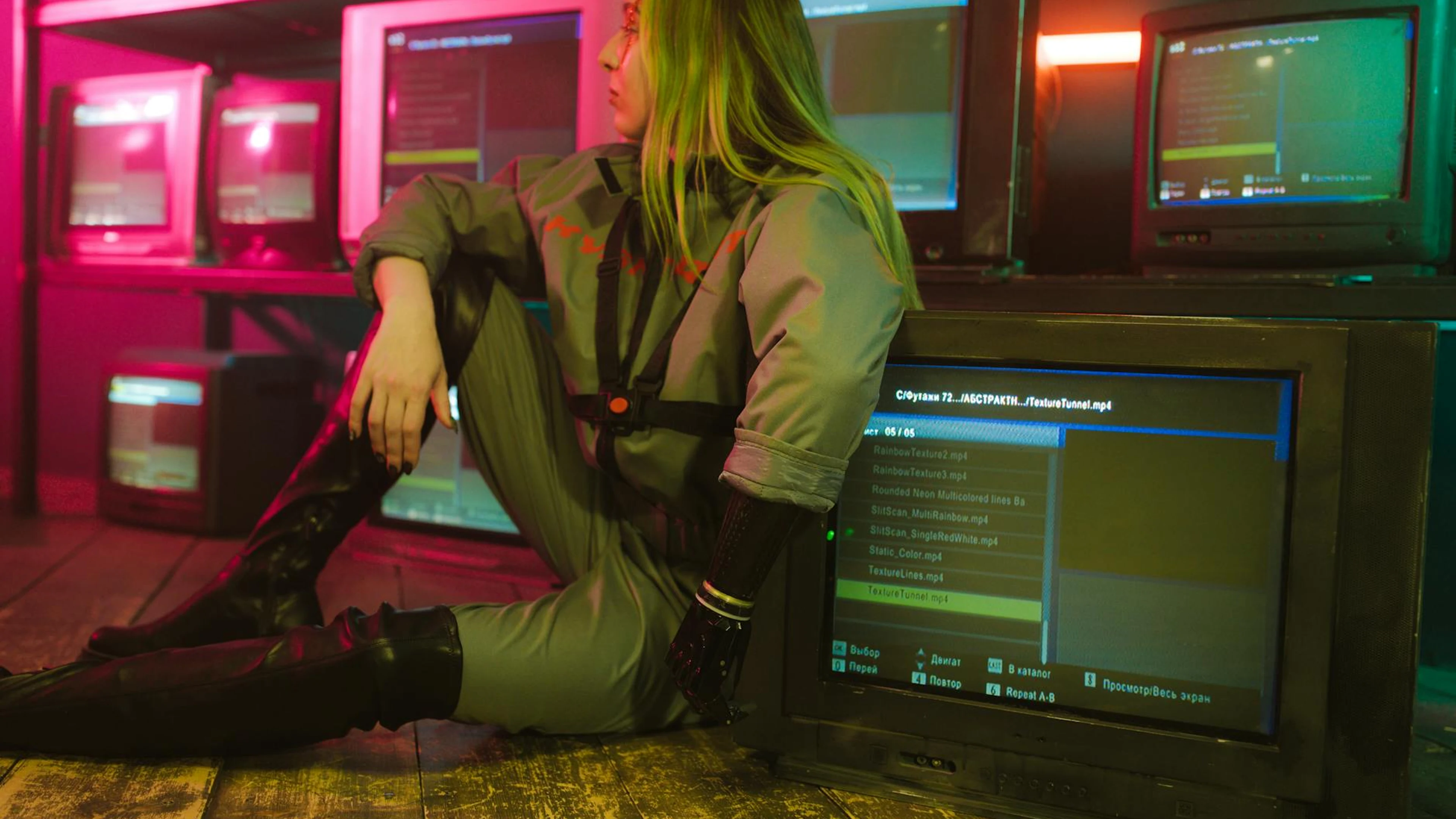 Woman in cyberpunk attire sits surrounded by vintage TVs in a neon-lit room, evo - free 4K Ultra HD gaming wallpaper for desktop