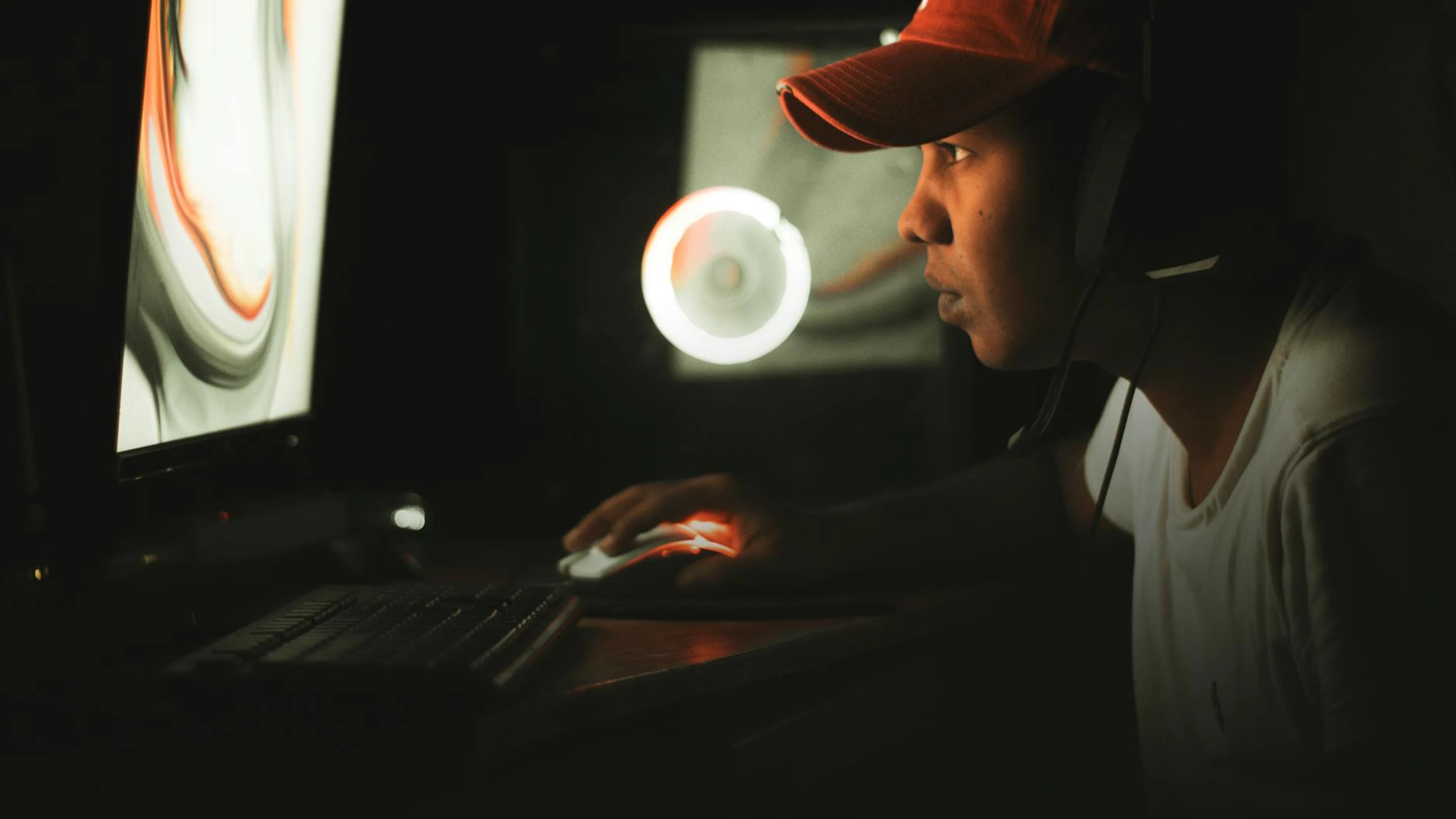 Young man gaming intensely in a dark room with neon lights, side view shot. - free 4K Ultra HD gaming wallpaper for desktop