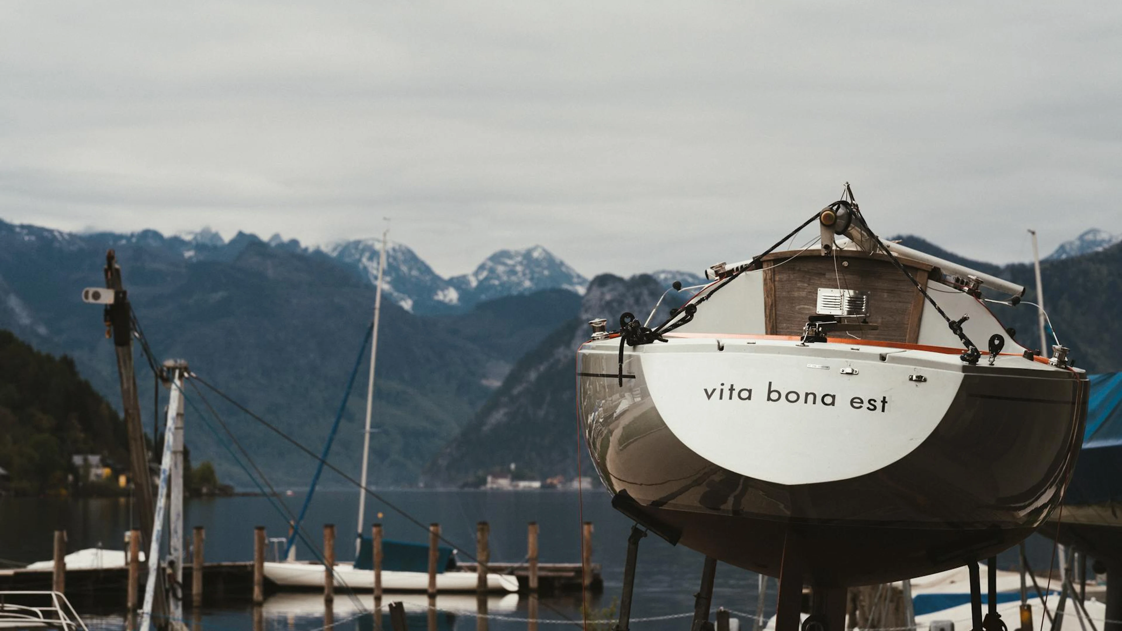 A boat named 'Vita Bona Est' docked with stunning Alpine backdrop in Gmunden, Au - free 4K Ultra HD lake wallpaper for desktop