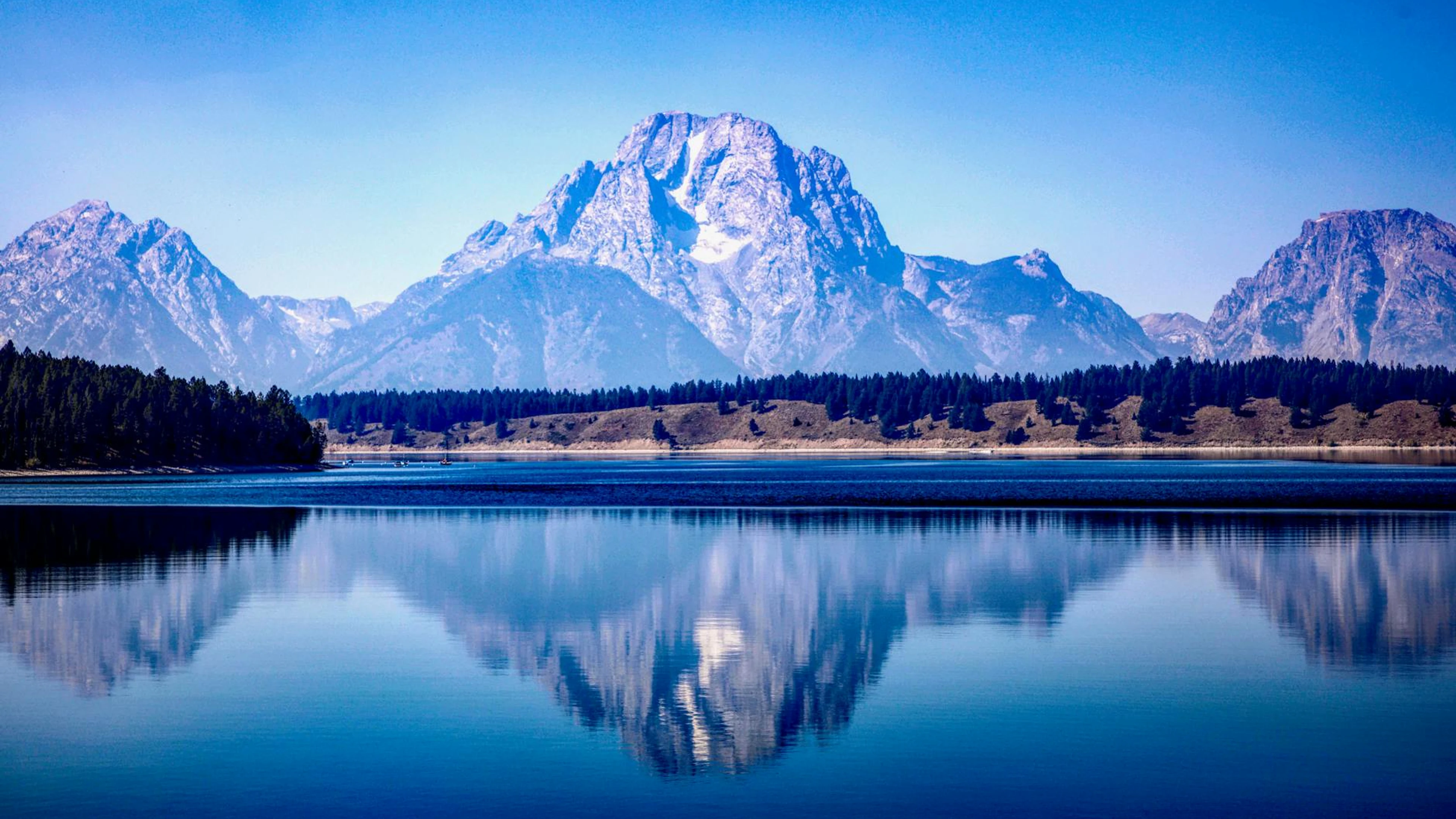 A peaceful view of Grand Teton mountains reflected in a placid lake under a clea - free 4K Ultra HD lake wallpaper for desktop