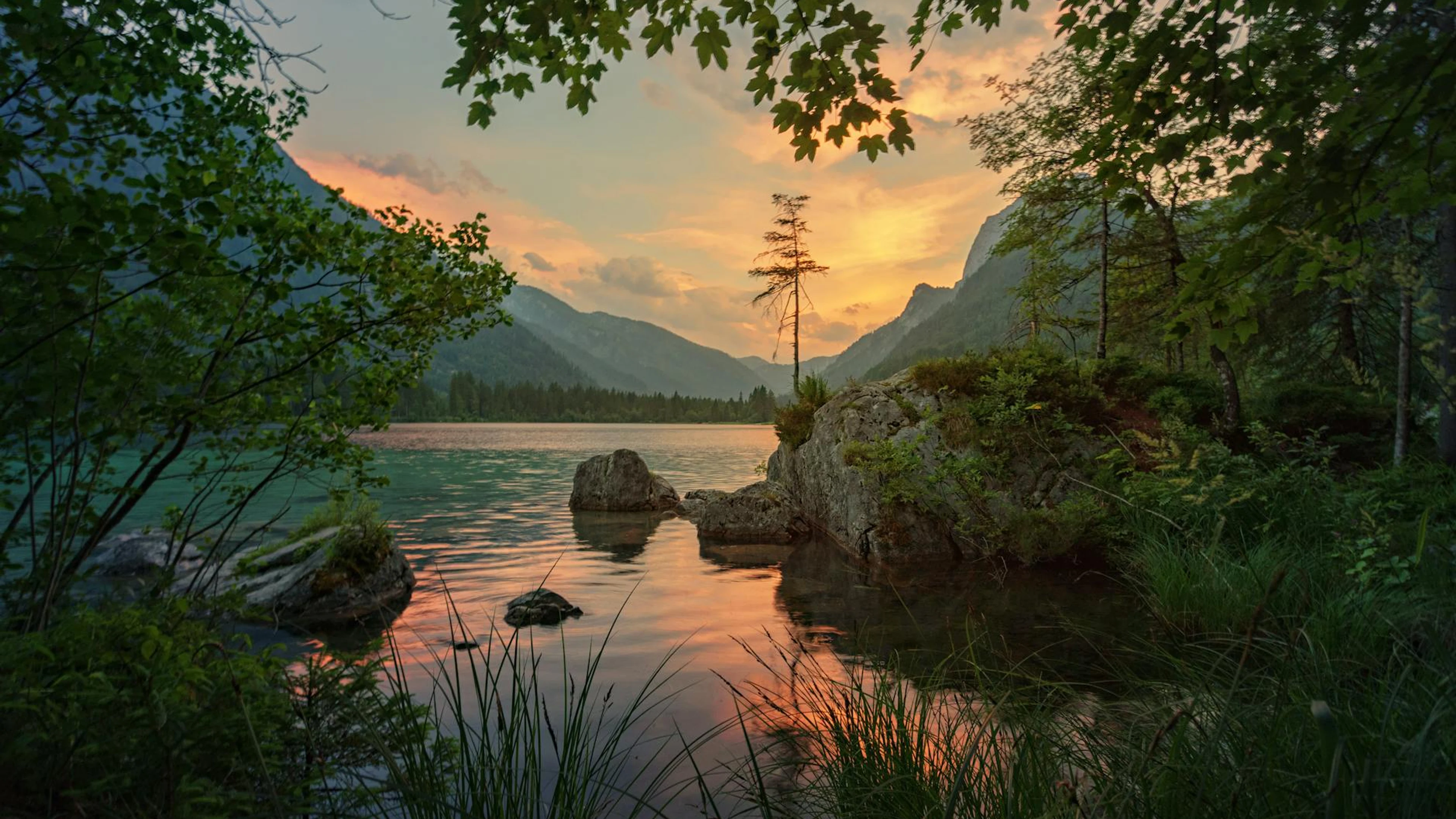 Peaceful sunset over a lake surrounded by mountains and lush greenery, capturing - free 4K Ultra HD lake wallpaper for desktop