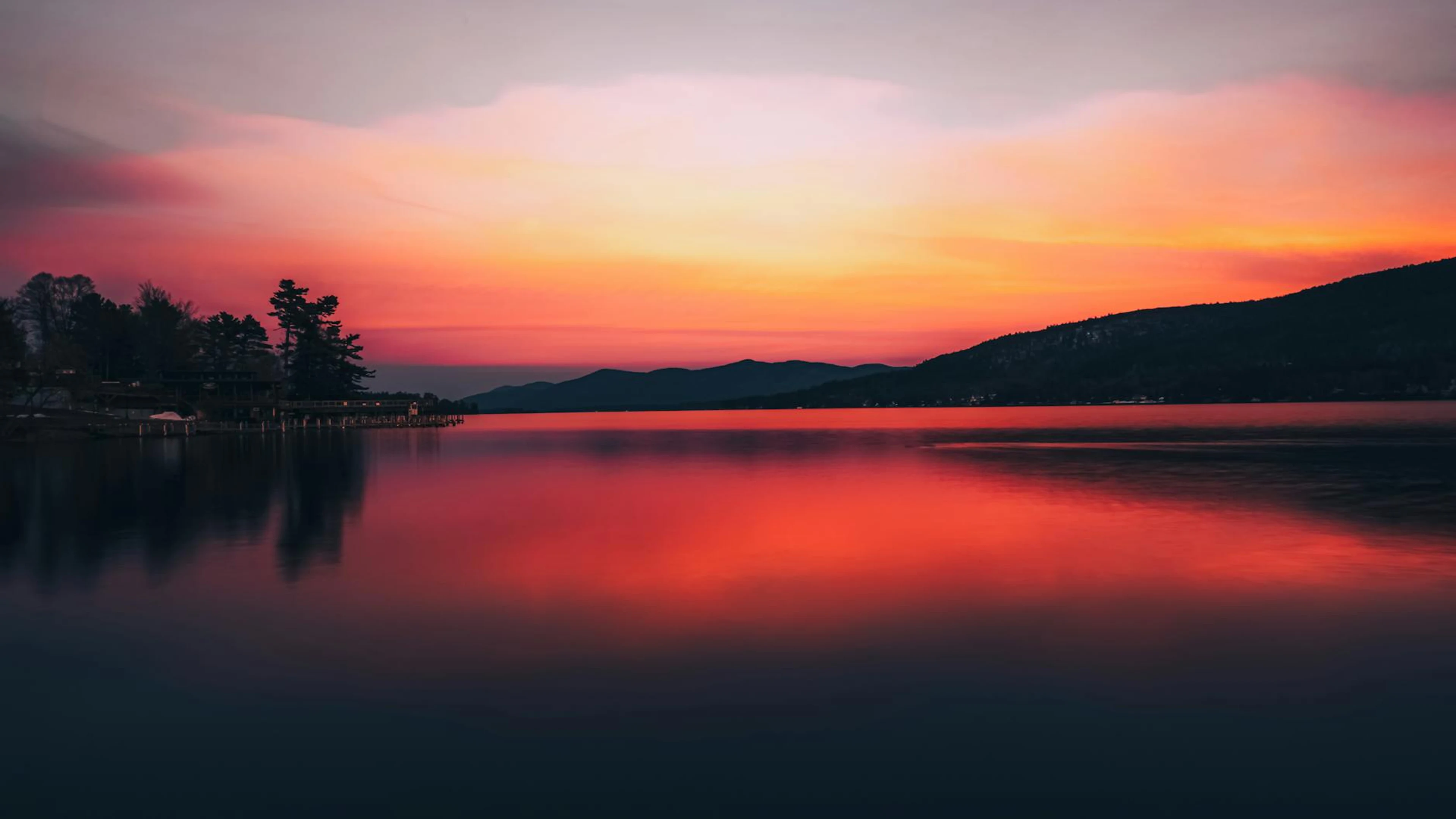 Stunning sunset over a tranquil lake with vibrant colors and serene reflections - free 4K Ultra HD lake wallpaper for desktop