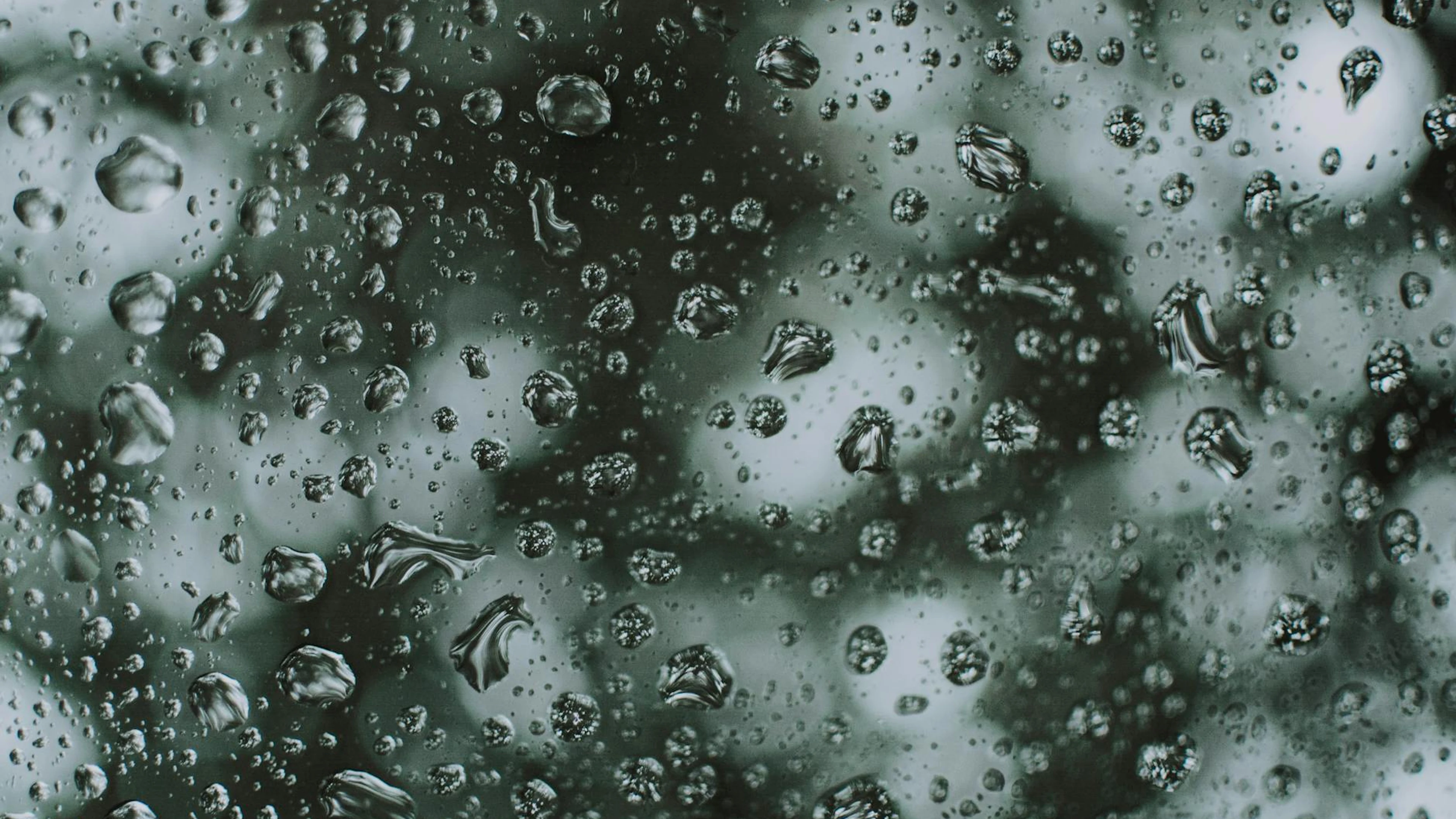 Artistic close-up photo capturing raindrops on a glass surface creating a textur - free 4K Ultra HD macro wallpaper for desktop