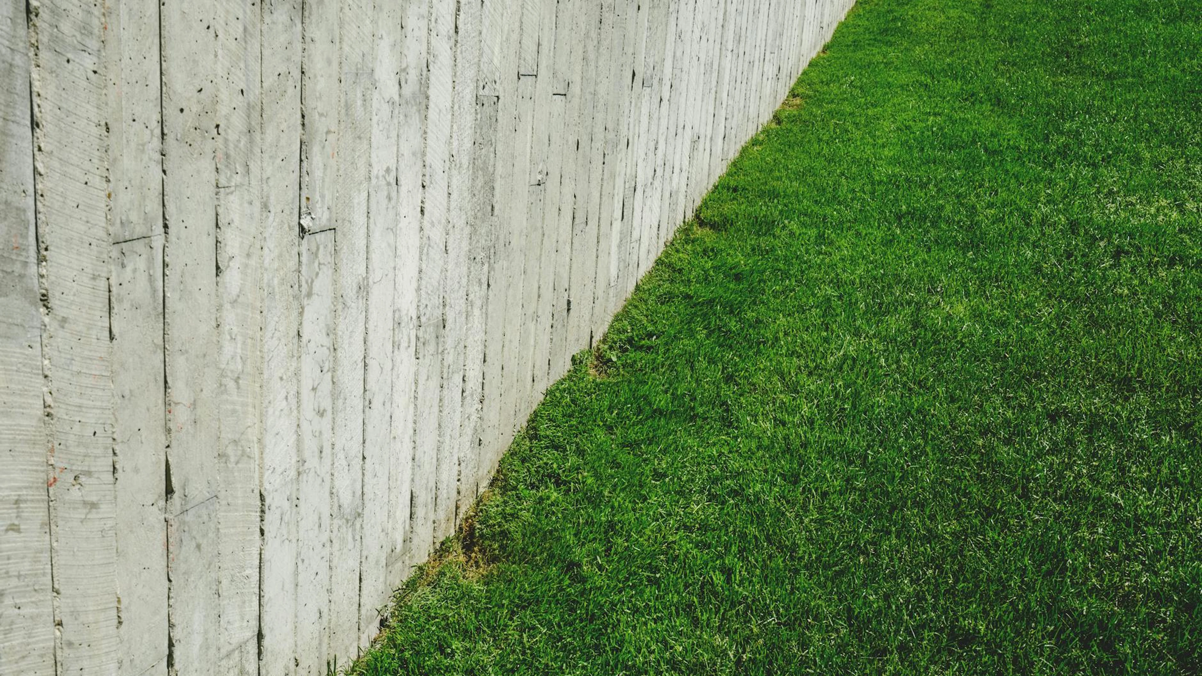 A minimalist outdoor scene featuring a wooden fence alongside a lush green lawn. - free 4K Ultra HD minimal wallpaper for desktop