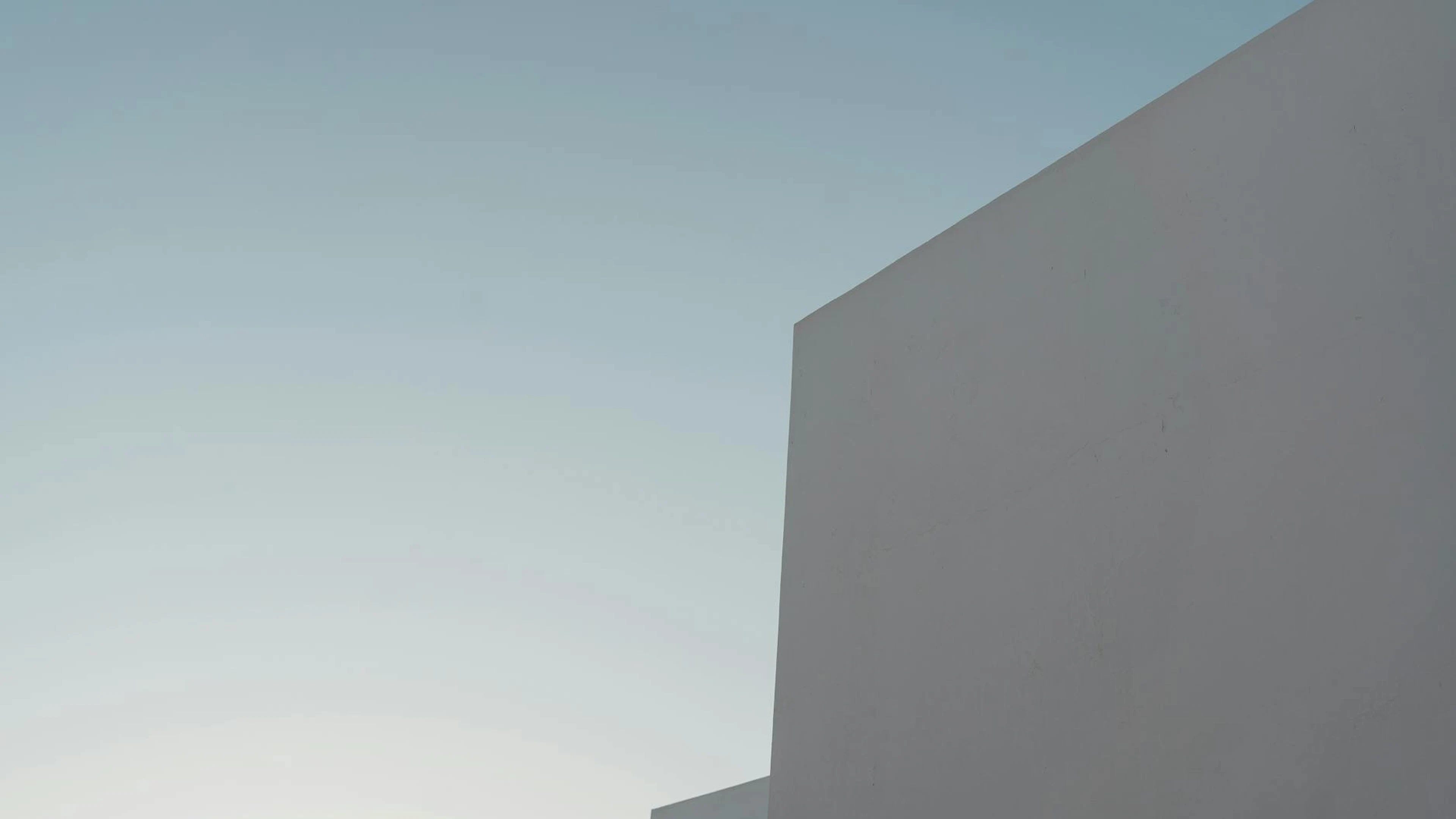 A minimalist view of a modern building's facade under a clear blue sky. - free 4K Ultra HD minimal wallpaper for desktop