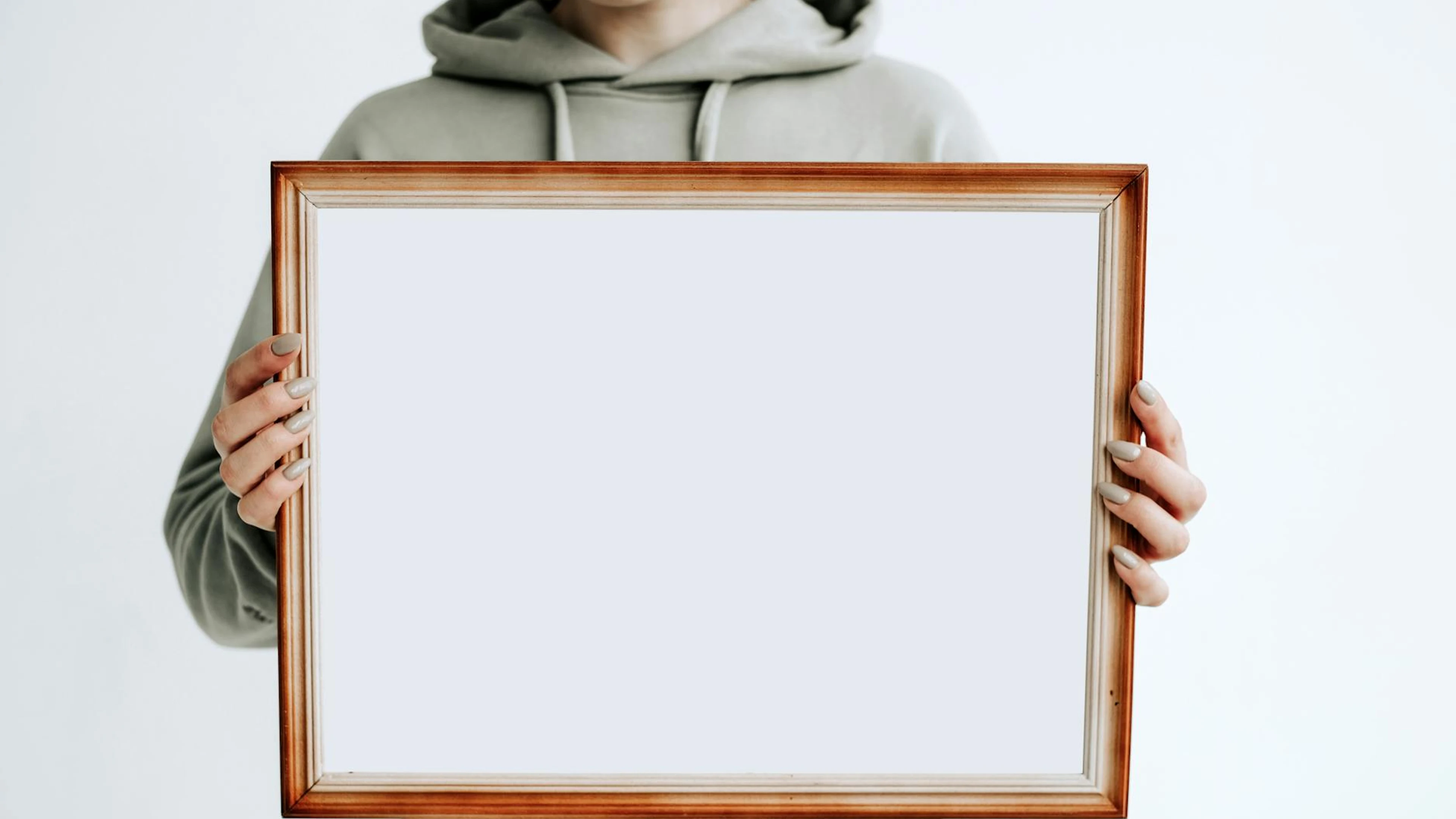 A person wearing a hoodie holds a blank wooden frame, ideal for mockups or art d - free 4K Ultra HD minimal wallpaper for desktop