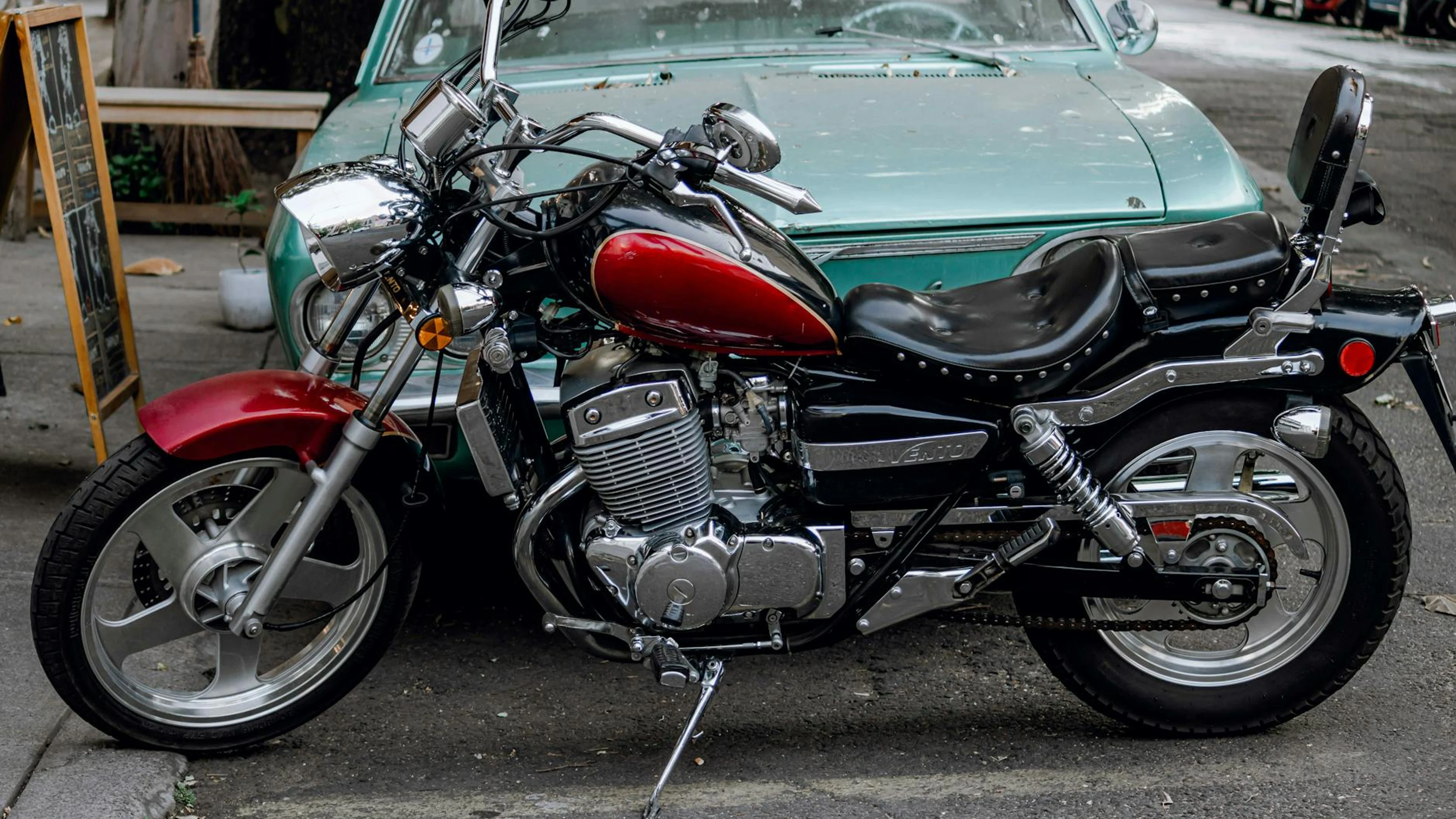 A sleek vintage motorcycle parked on a city street, adjacent to a classic car. - free 4K Ultra HD motorcycle wallpaper for desktop