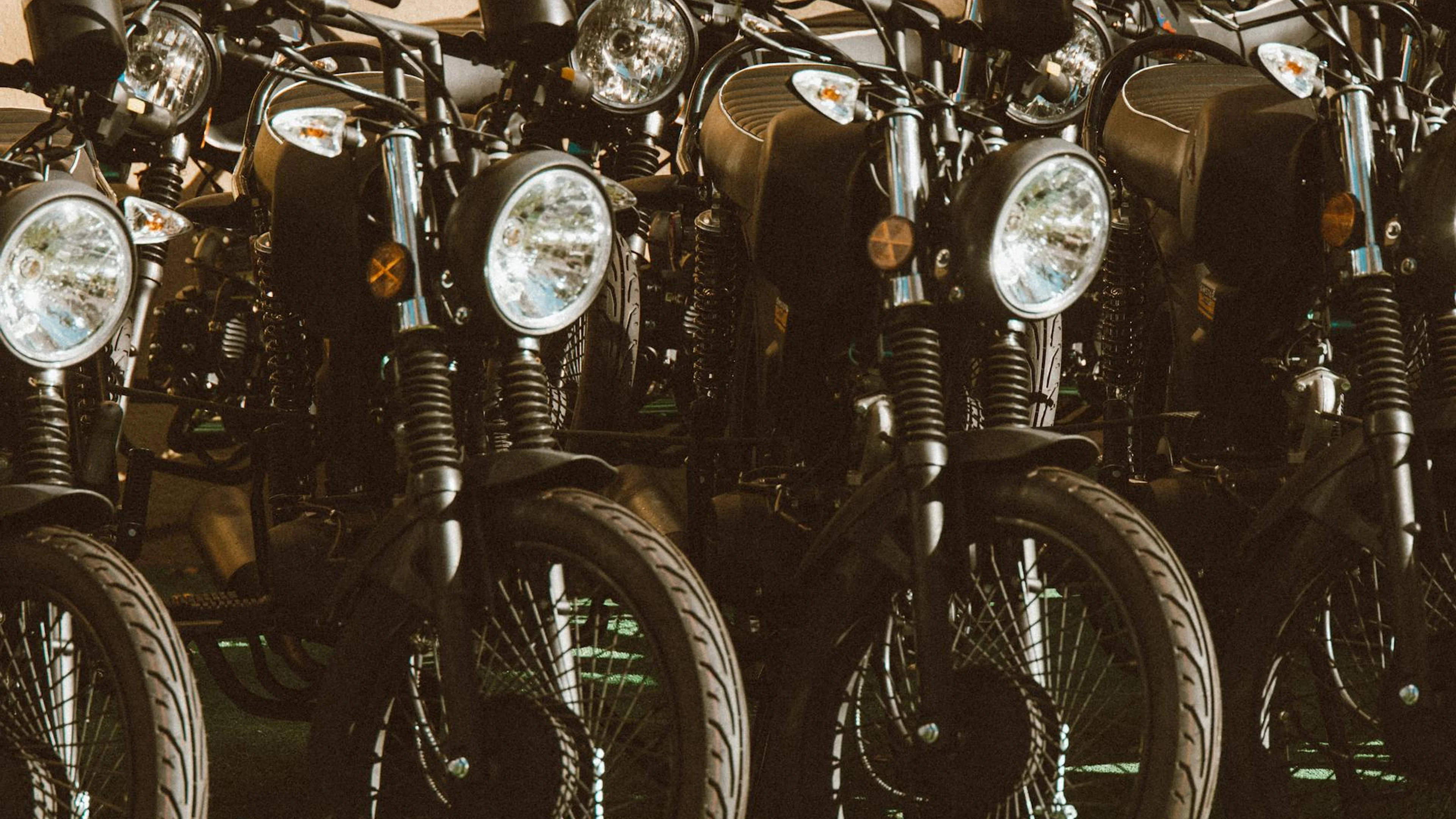 A stylish lineup of vintage motorcycles parked in a sunlit outdoor setting. - free 4K Ultra HD motorcycle wallpaper for desktop