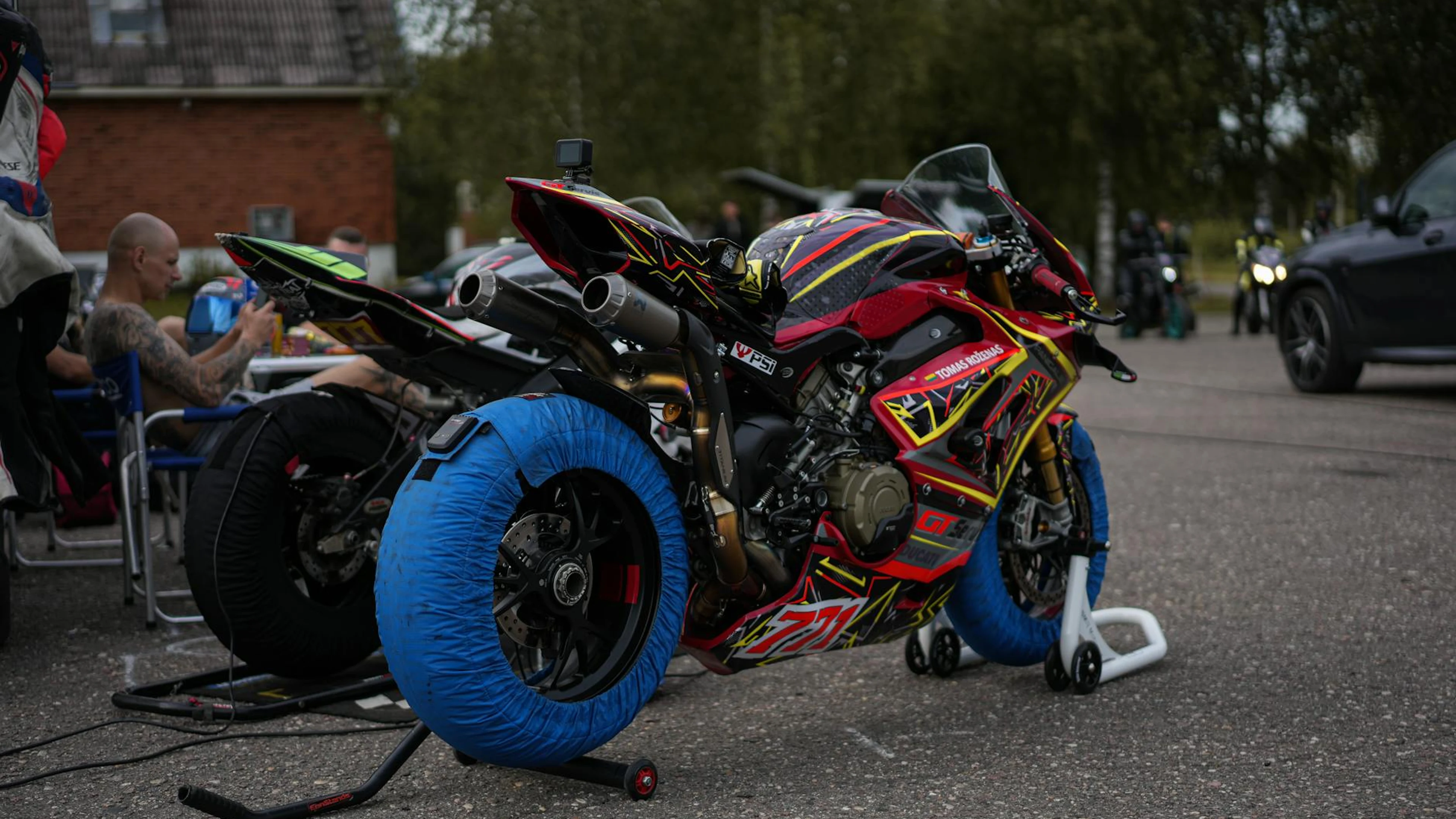 A vibrant racing motorcycle with tire heaters in a pit area, ready for the race. - free 4K Ultra HD motorcycle wallpaper for desktop