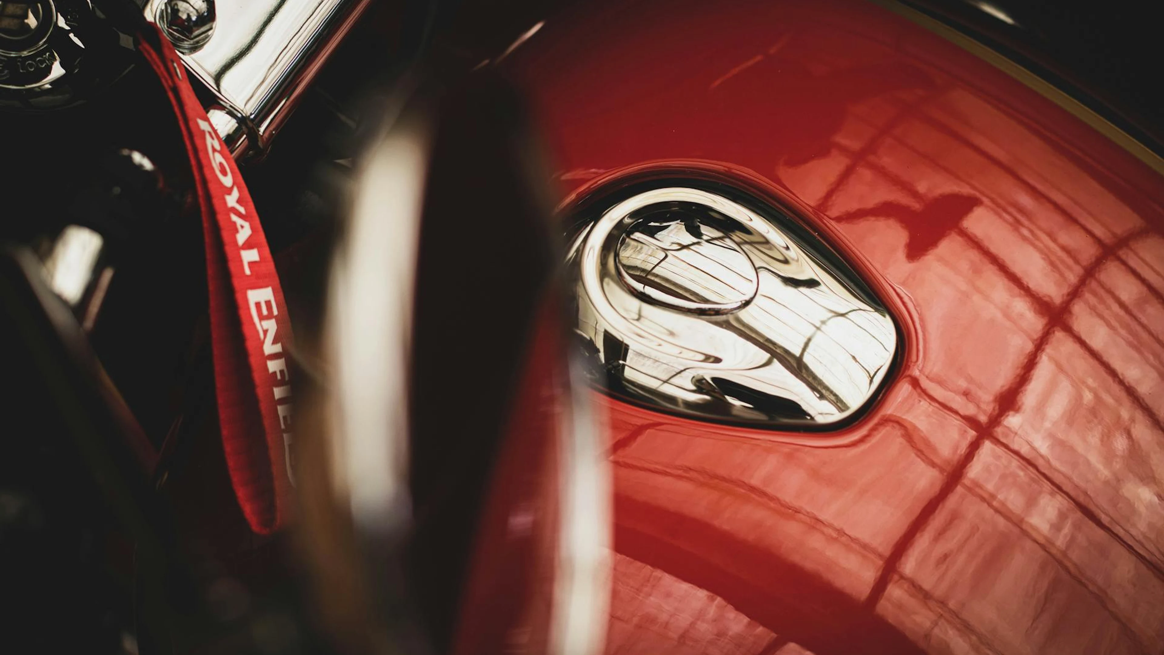 Detailed close-up of a classic red Royal Enfield motorcycle fuel tank featuring - free 4K Ultra HD motorcycle wallpaper for desktop