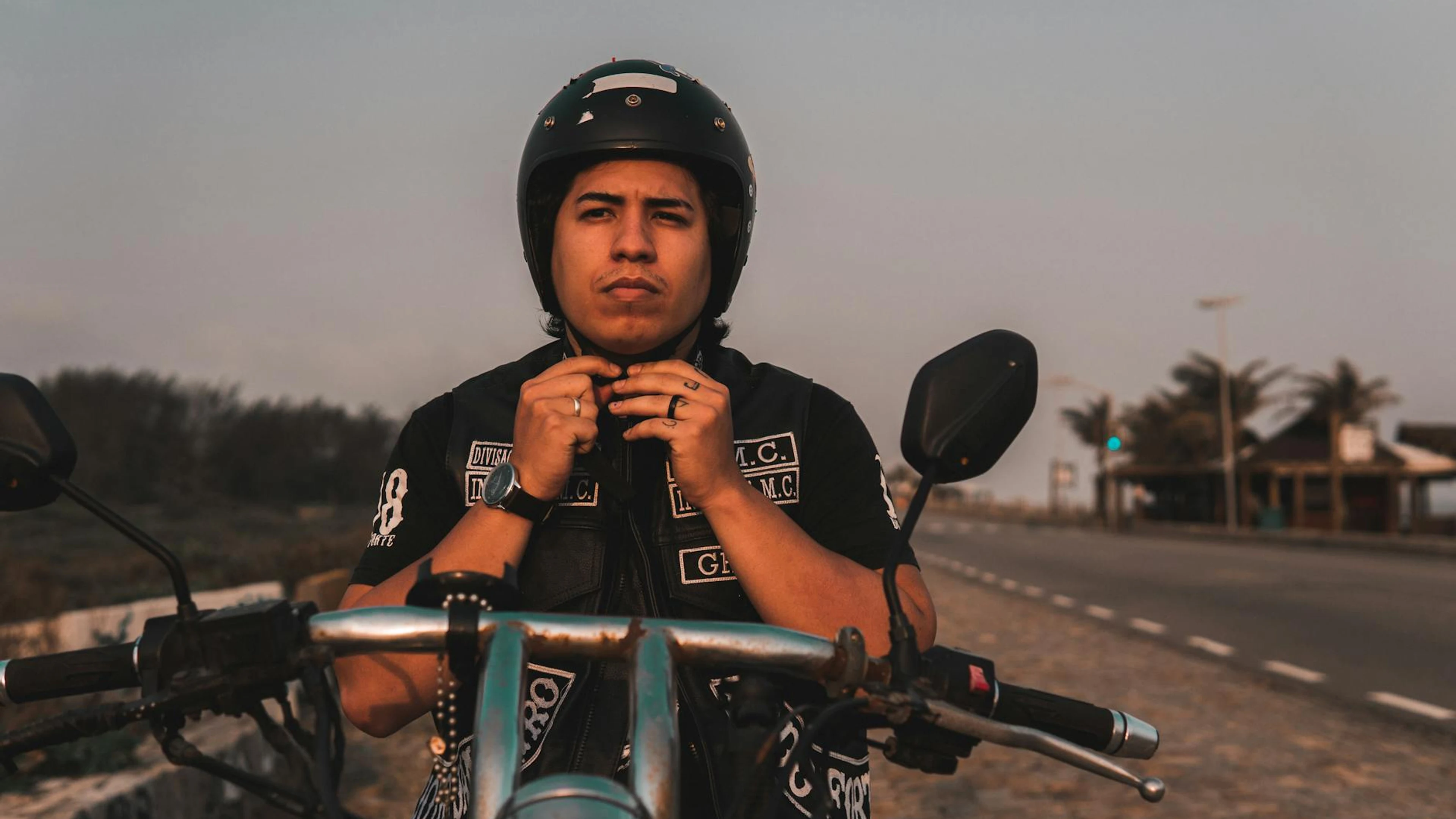 Man wearing a helmet adjusting it on his motorcycle during the day on an open ro - free 4K Ultra HD motorcycle wallpaper for desktop