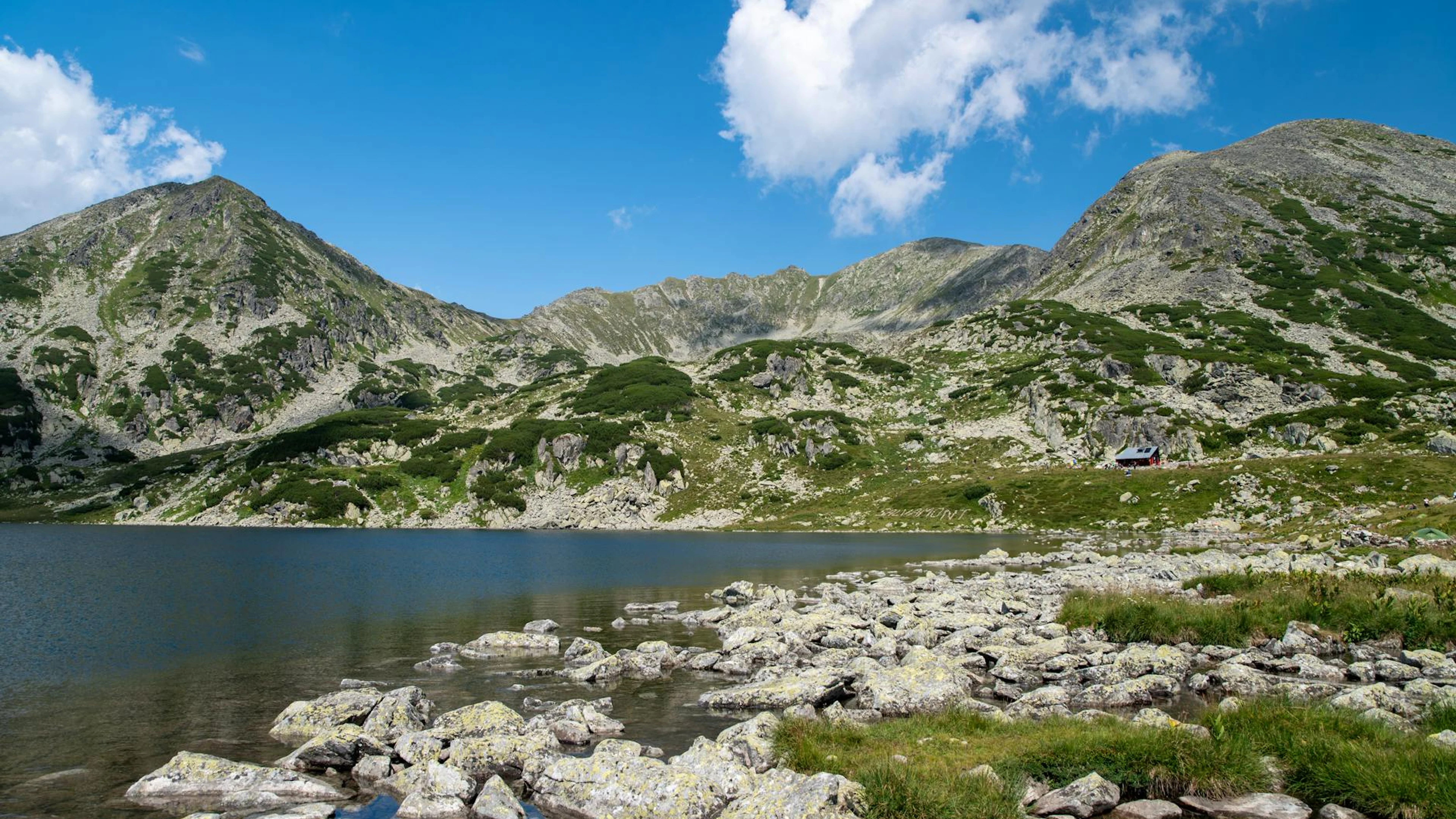 A serene alpine lake amid rocky mountains and clear blue skies, perfect for natu - free 4K Ultra HD mountain wallpaper for desktop