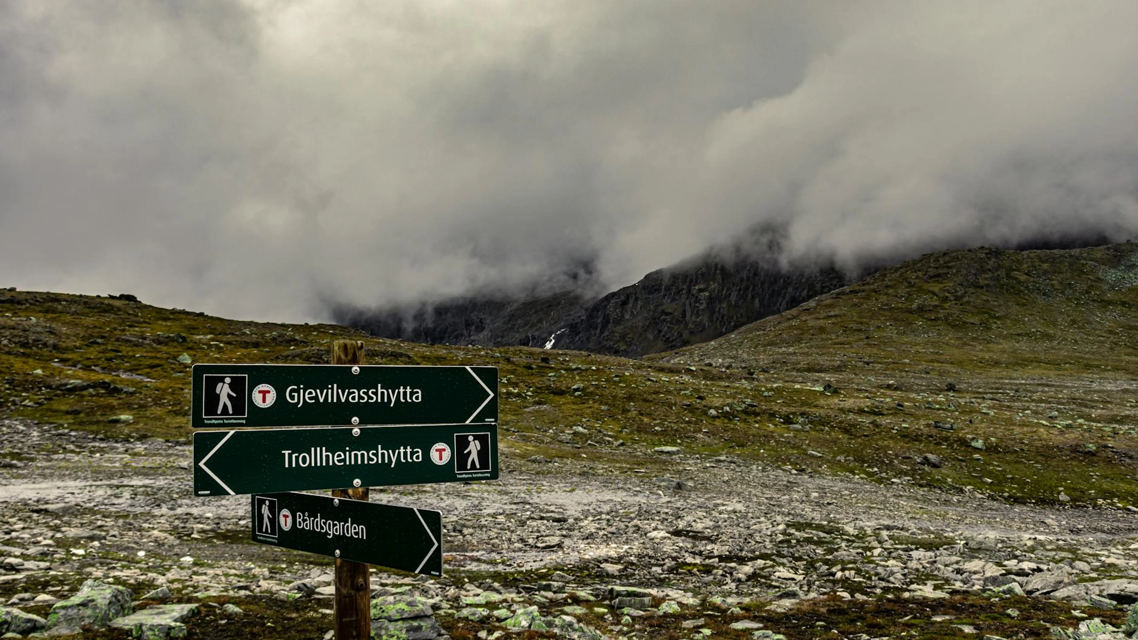 Mountain trail signage in Gjevilvasshytta, Trøndelag, Norway amidst cloudy skies - free 4K Ultra HD mountain wallpaper for desktop