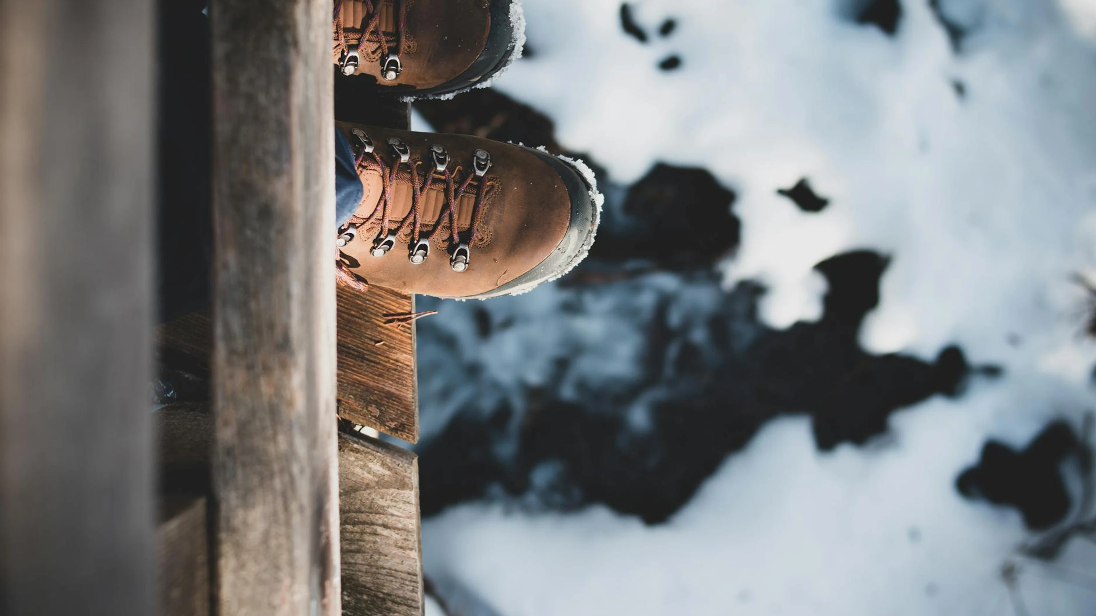 Top view of brown hiking boots on a wooden edge overlooking a snowy landscape, c - free 4K Ultra HD mountain wallpaper for desktop