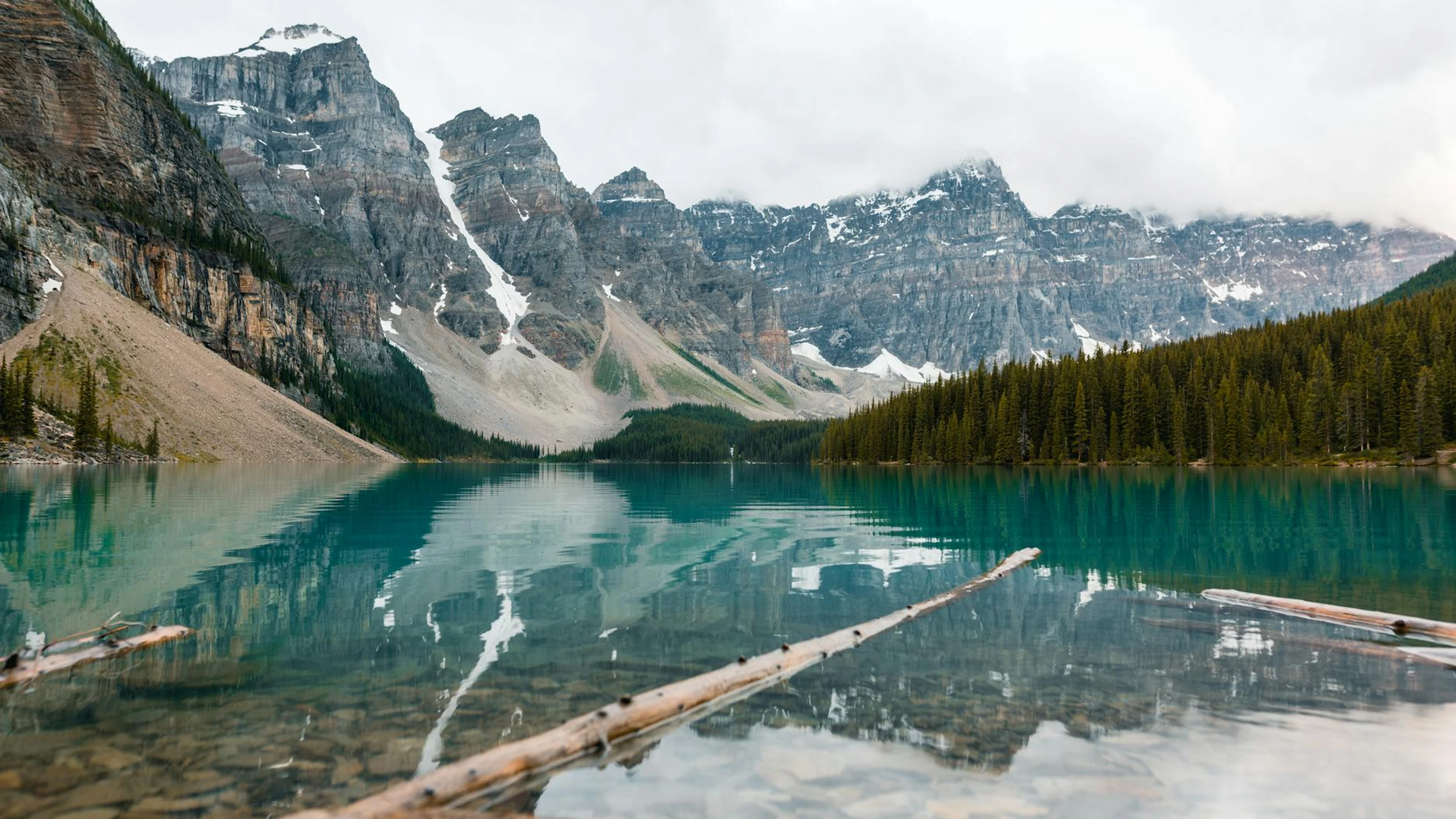 Tranquil Moraine Lake with Rocky Mountains reflecting under a cloudy sky in Banf - free 4K Ultra HD mountain wallpaper for desktop