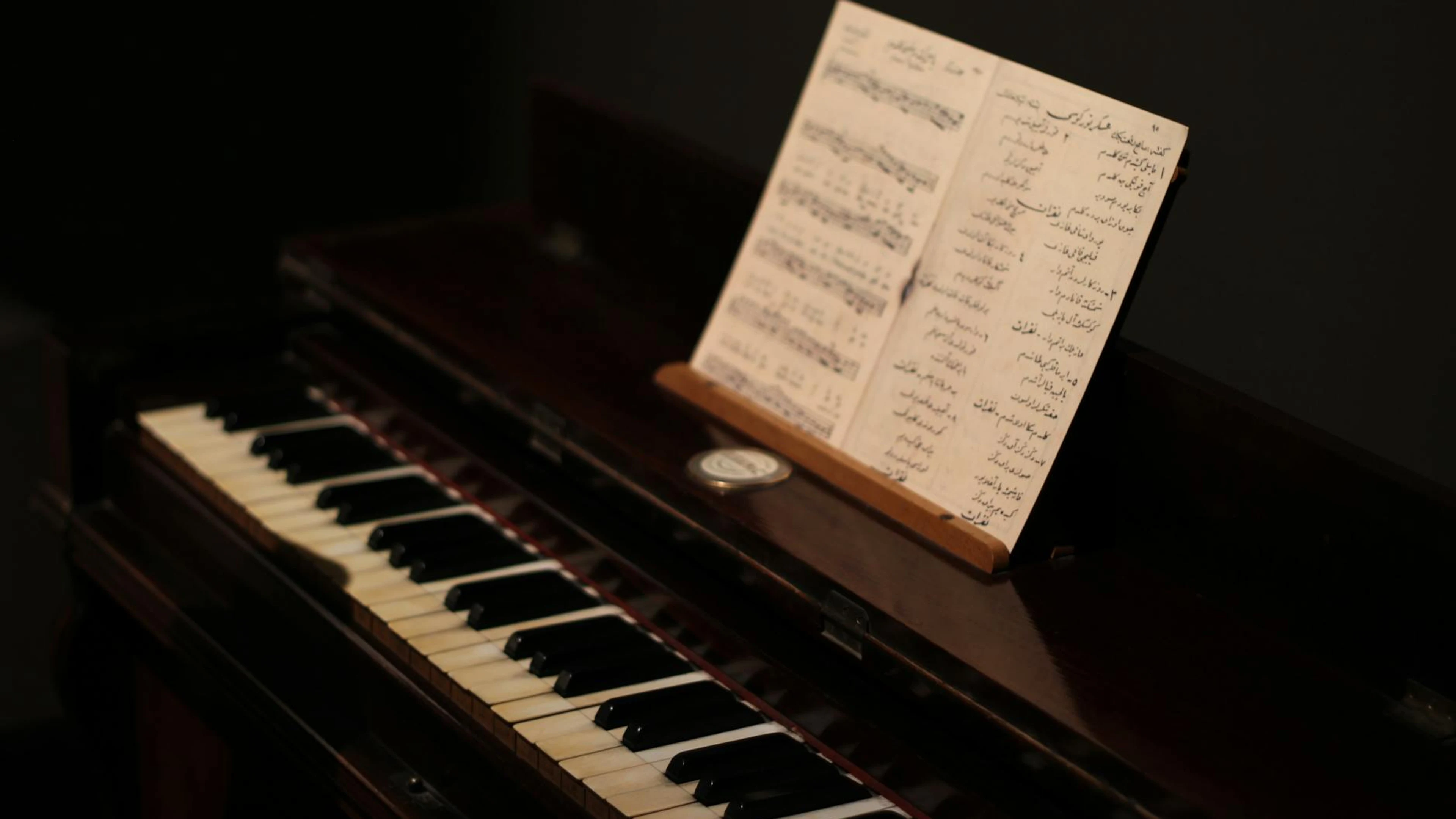 A close-up of a vintage piano with sheet music, highlighting its nostalgic charm - free 4K Ultra HD music wallpaper for desktop
