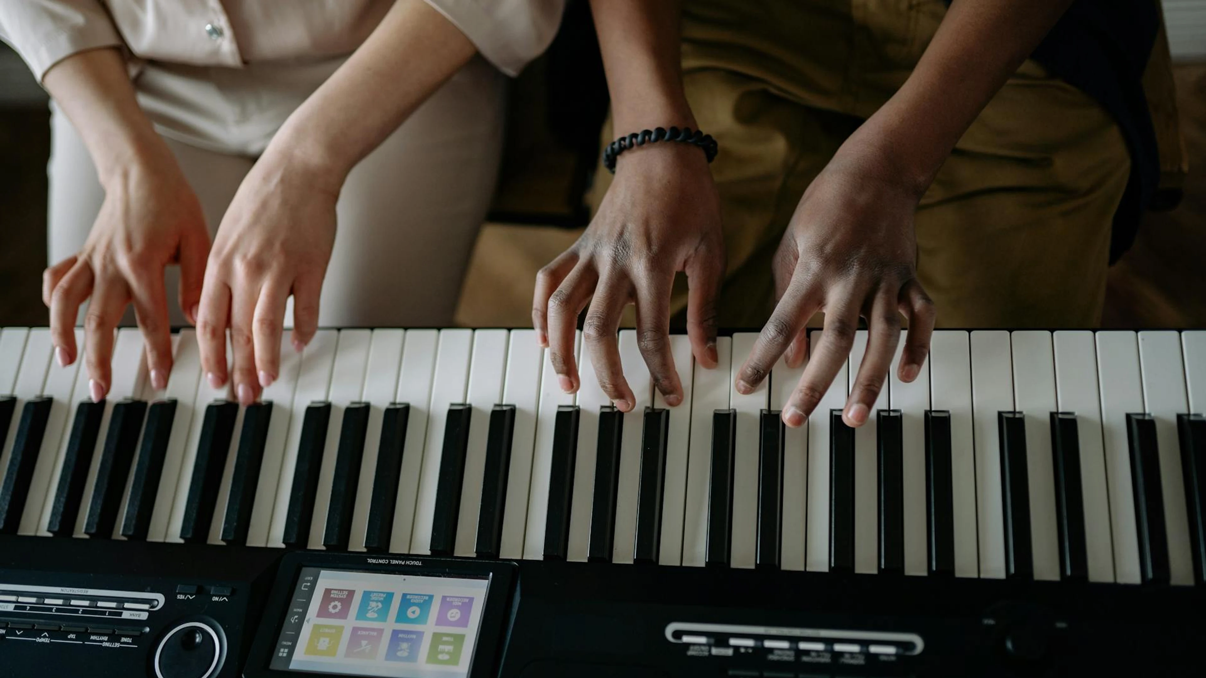 A close-up of two people playing piano together indoors, showcasing their hands - free 4K Ultra HD music wallpaper for desktop