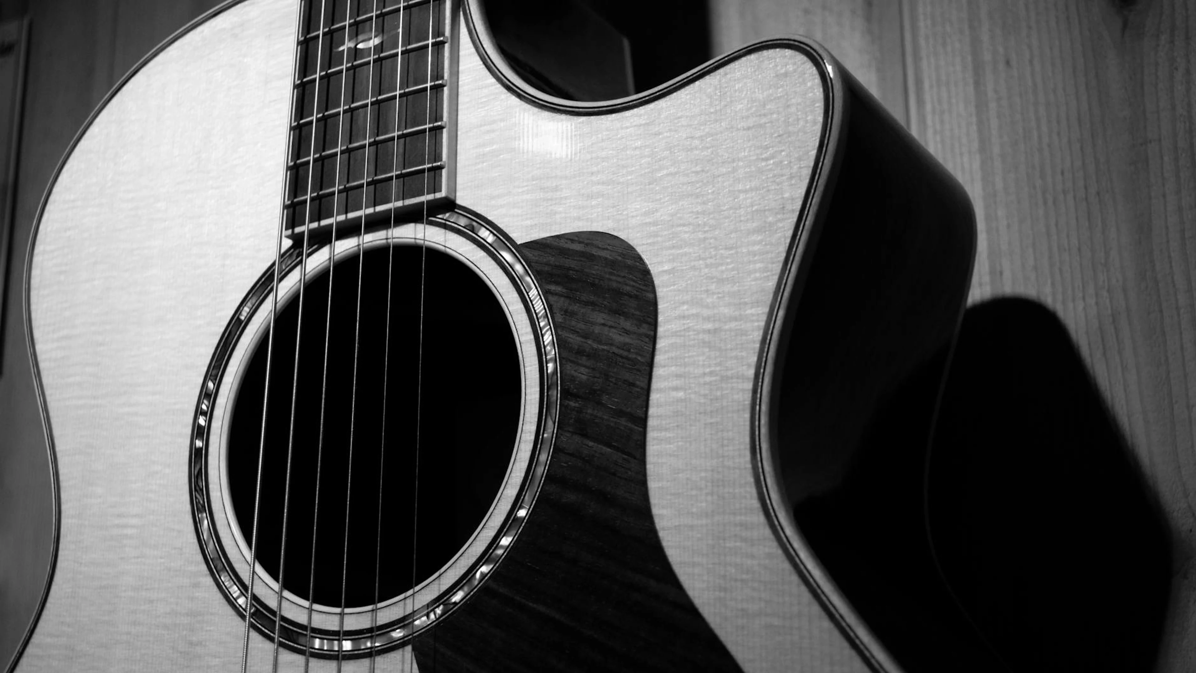 A detailed black and white close-up of a classic acoustic guitar, highlighting i - free 4K Ultra HD music wallpaper for desktop