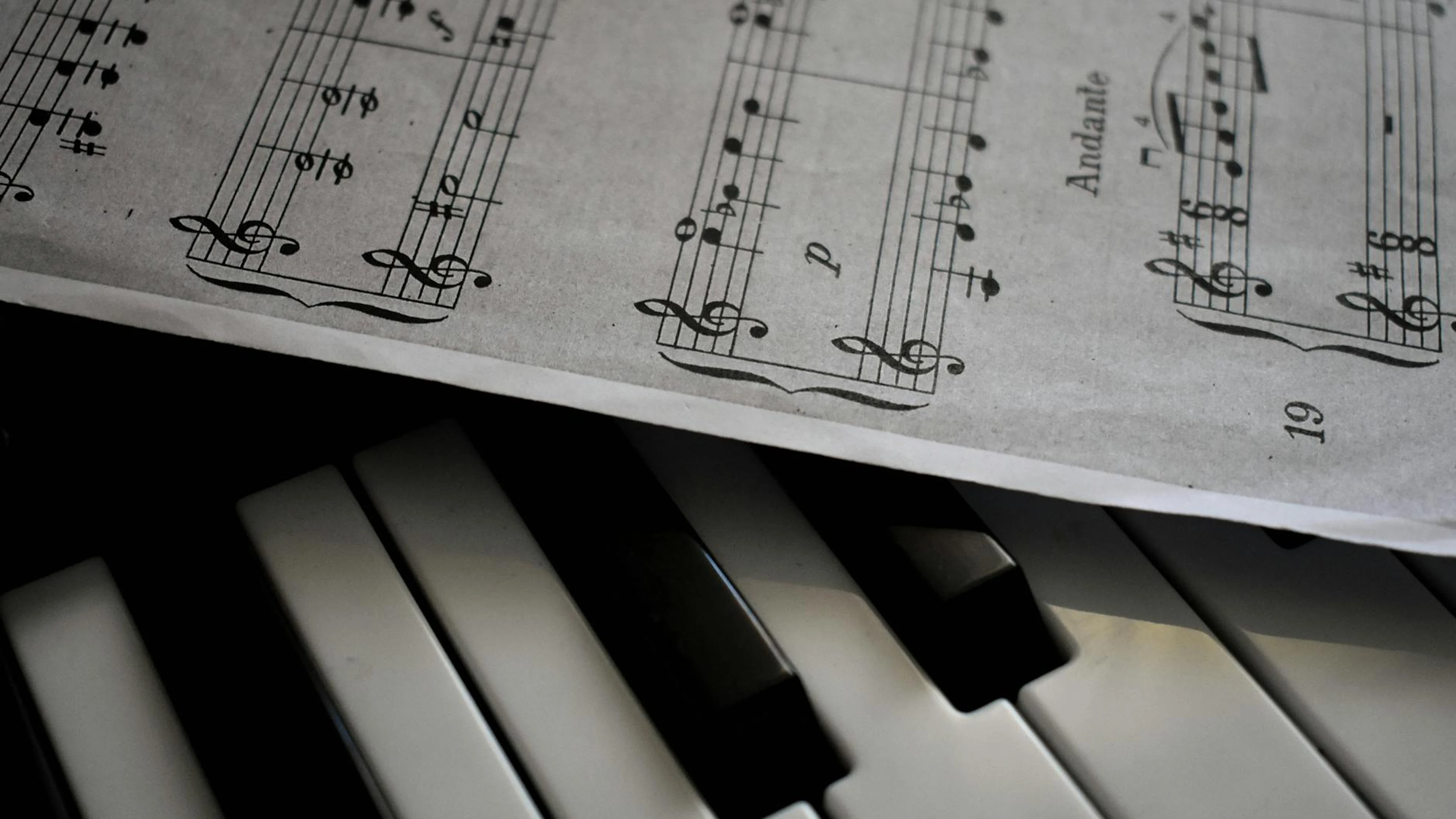 A detailed view of piano keys alongside a sheet of musical notation, emphasizing - free 4K Ultra HD music wallpaper for desktop