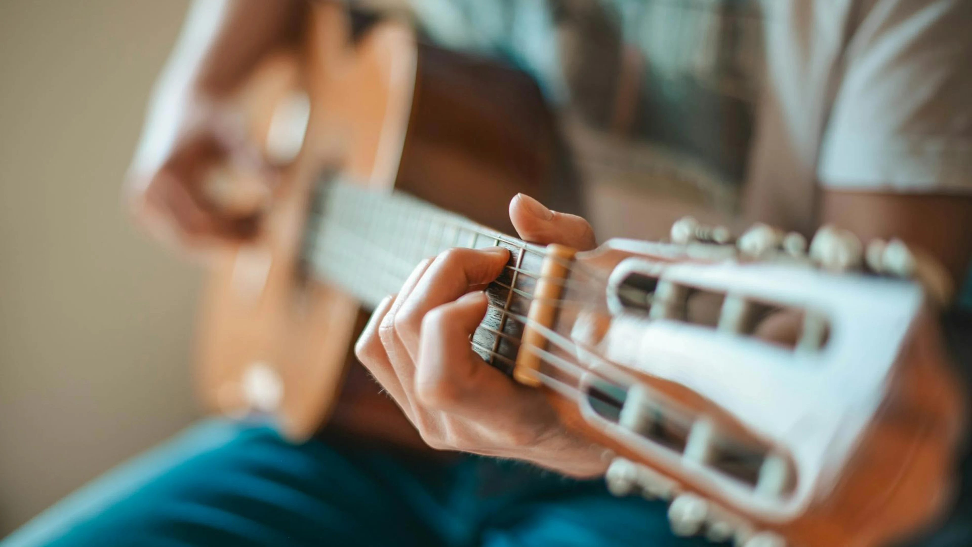 A person playing an acoustic guitar focusing on hand fretboard positioning. - free 4K Ultra HD music wallpaper for desktop