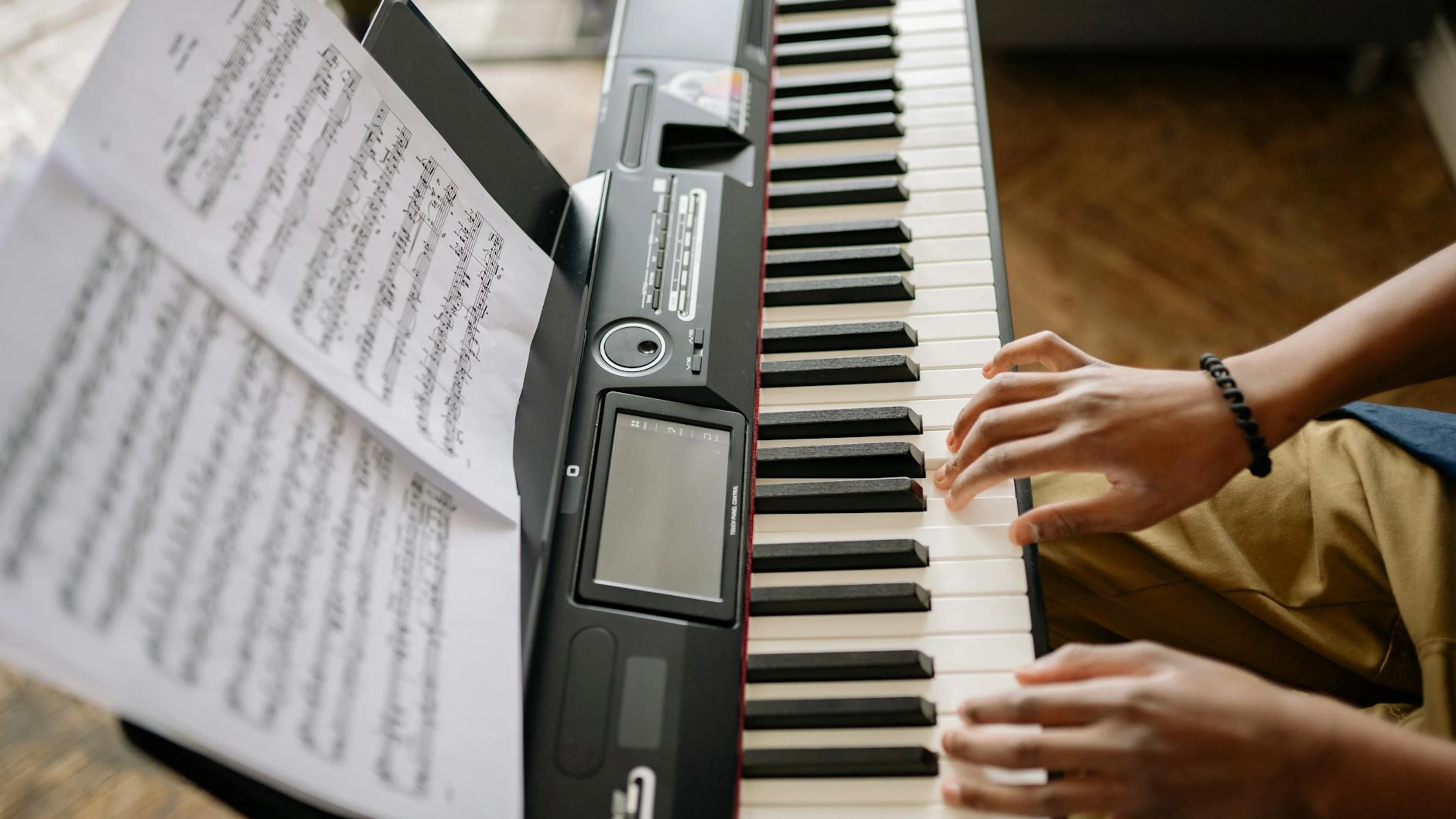Close-up of hands playing a digital piano with sheet music in view. - free 4K Ultra HD music wallpaper for desktop