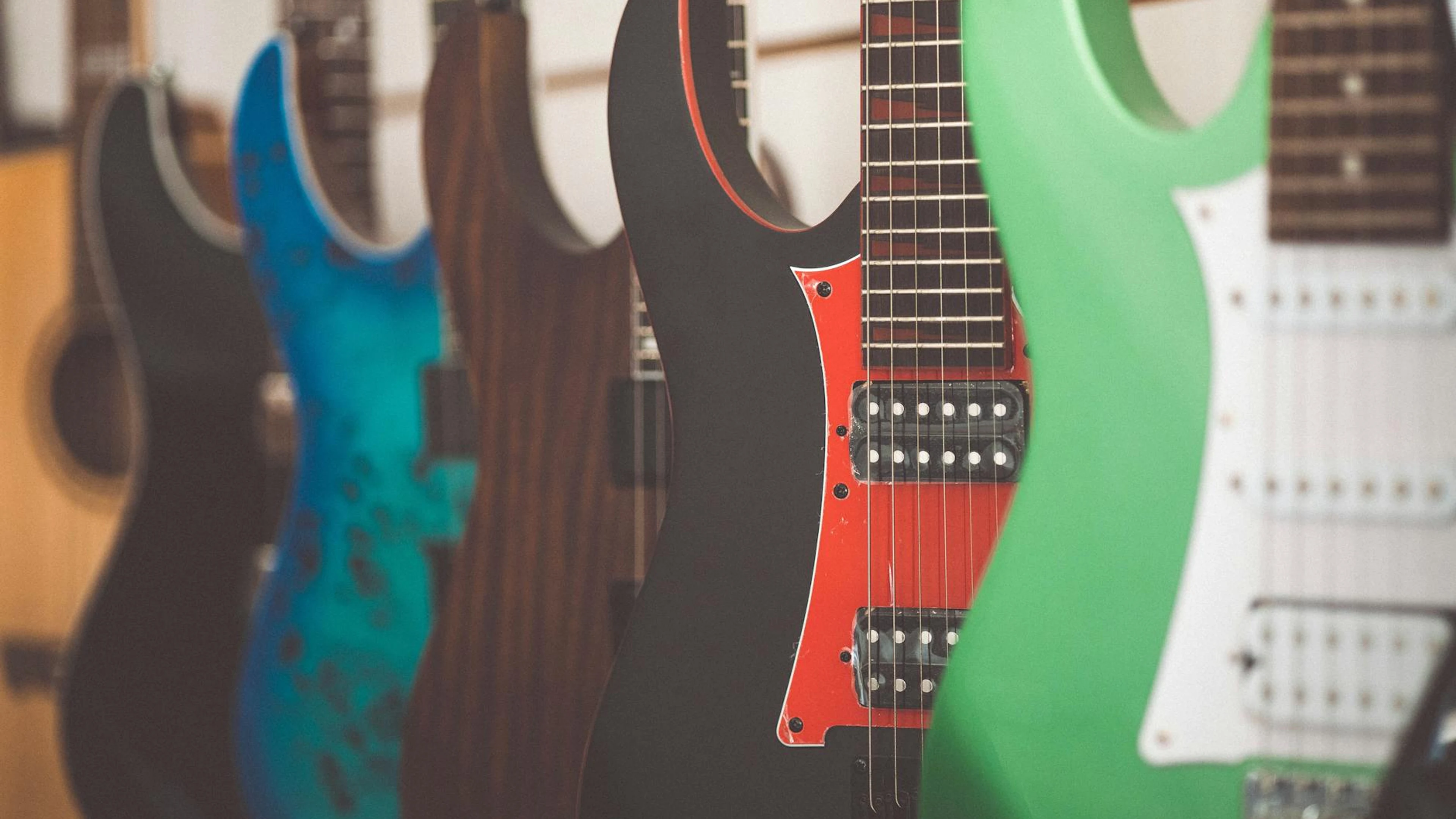 Colorful electric guitars lined up in a music store display, highlighting differ - free 4K Ultra HD music wallpaper for desktop