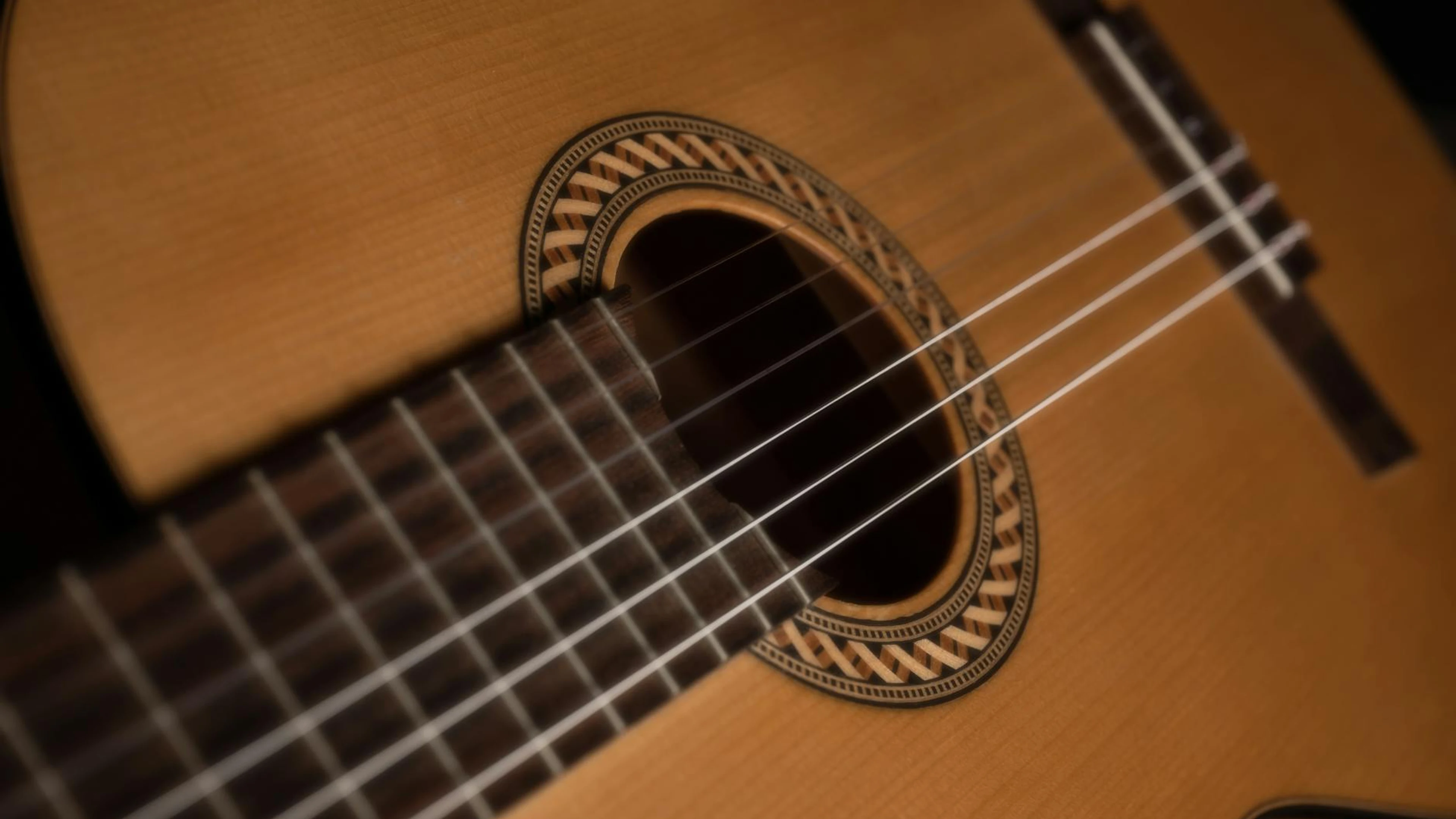 Detailed close-up of a classic acoustic guitar highlighting the strings and soun - free 4K Ultra HD music wallpaper for desktop