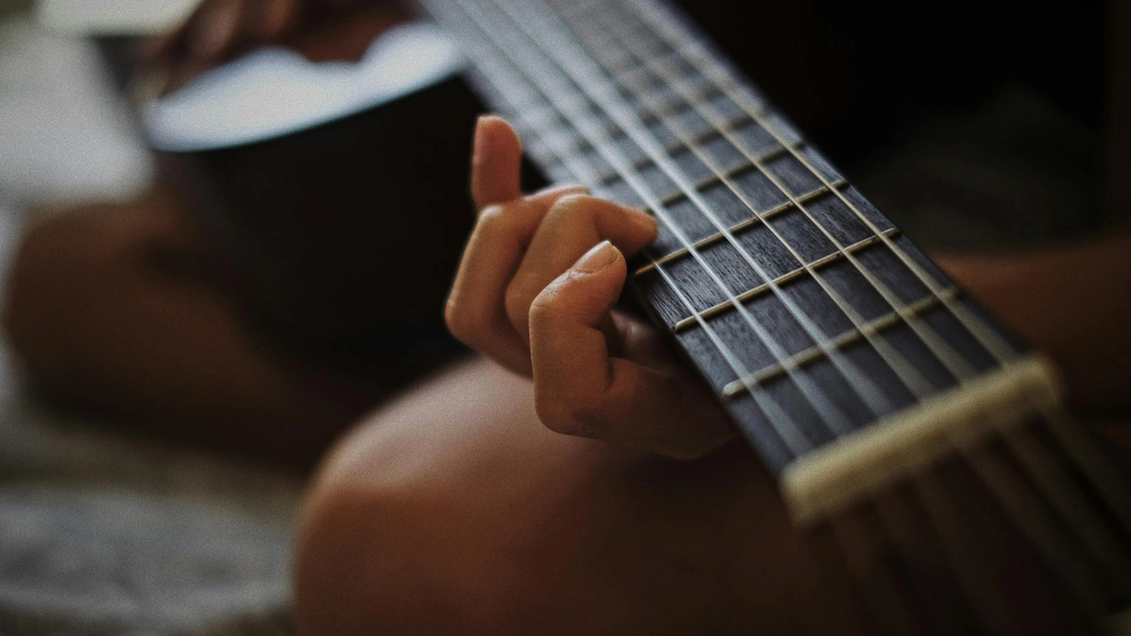 Detailed close-up of hands playing an acoustic guitar, emphasizing strings and f - free 4K Ultra HD music wallpaper for desktop
