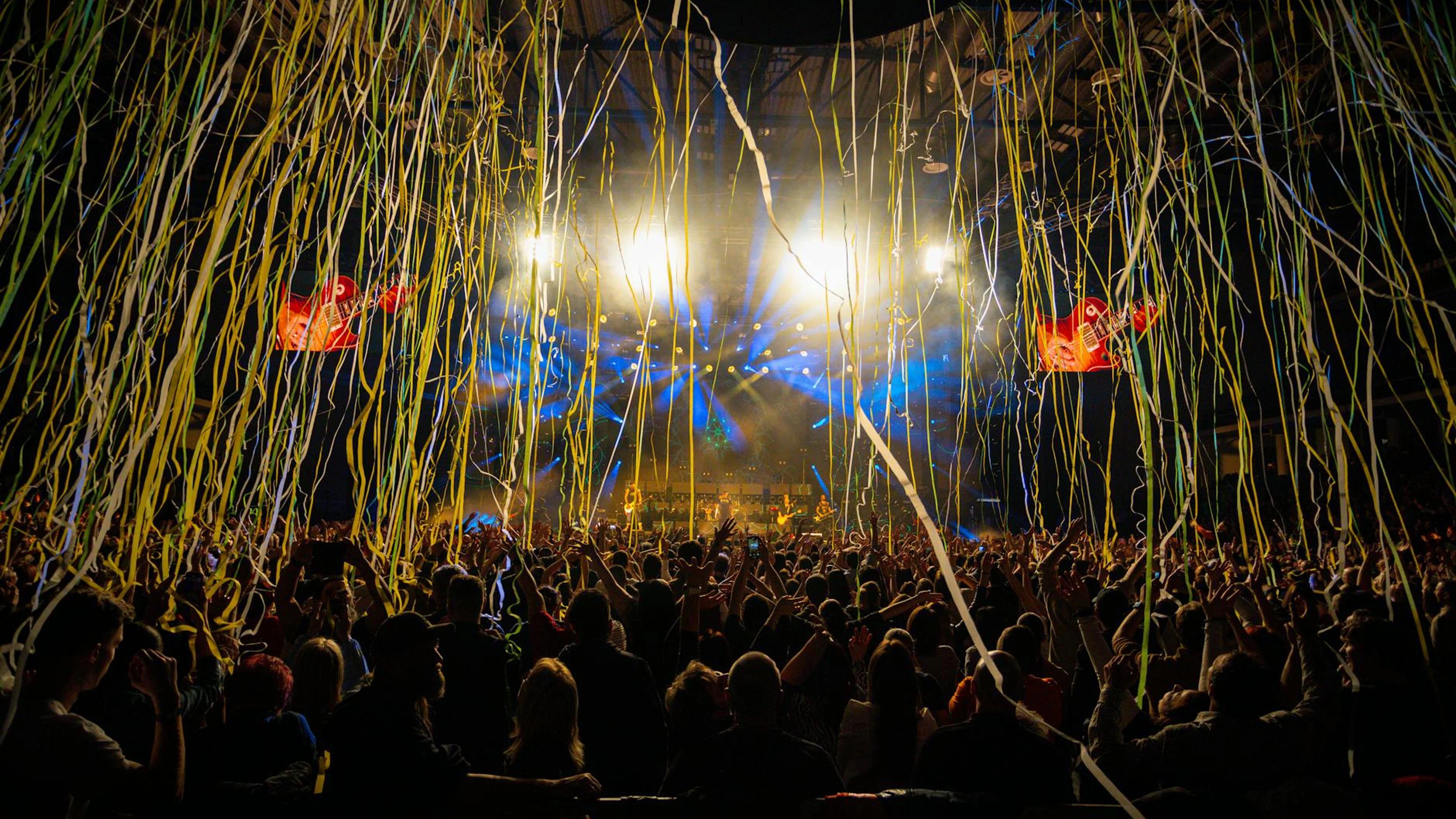 Dynamic concert scene with audience, vibrant lights, and cascading confetti. Cap - free 4K Ultra HD music wallpaper for desktop