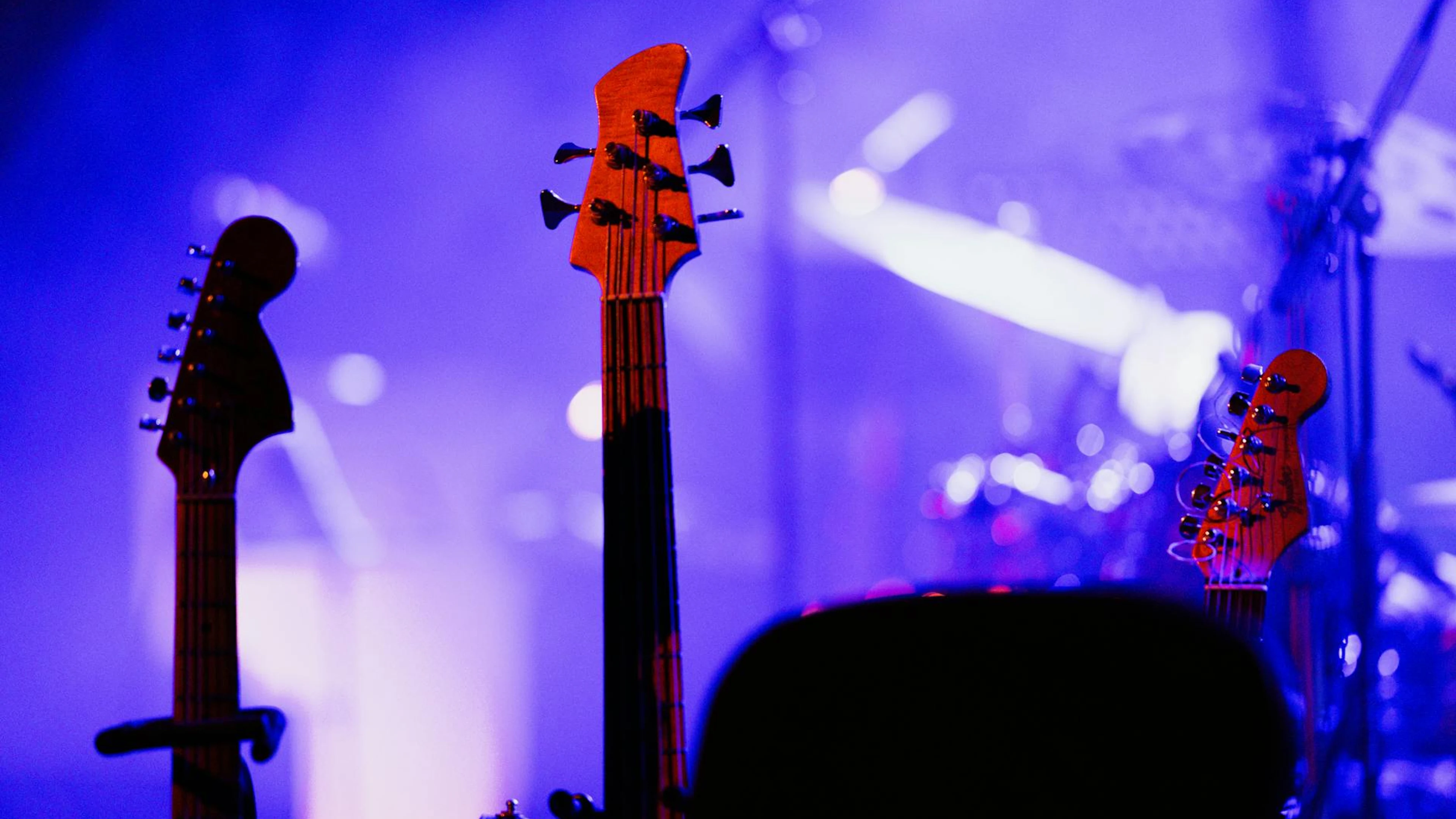 Electric guitars on stage under colorful concert lights, capturing the vibrant m - free 4K Ultra HD music wallpaper for desktop