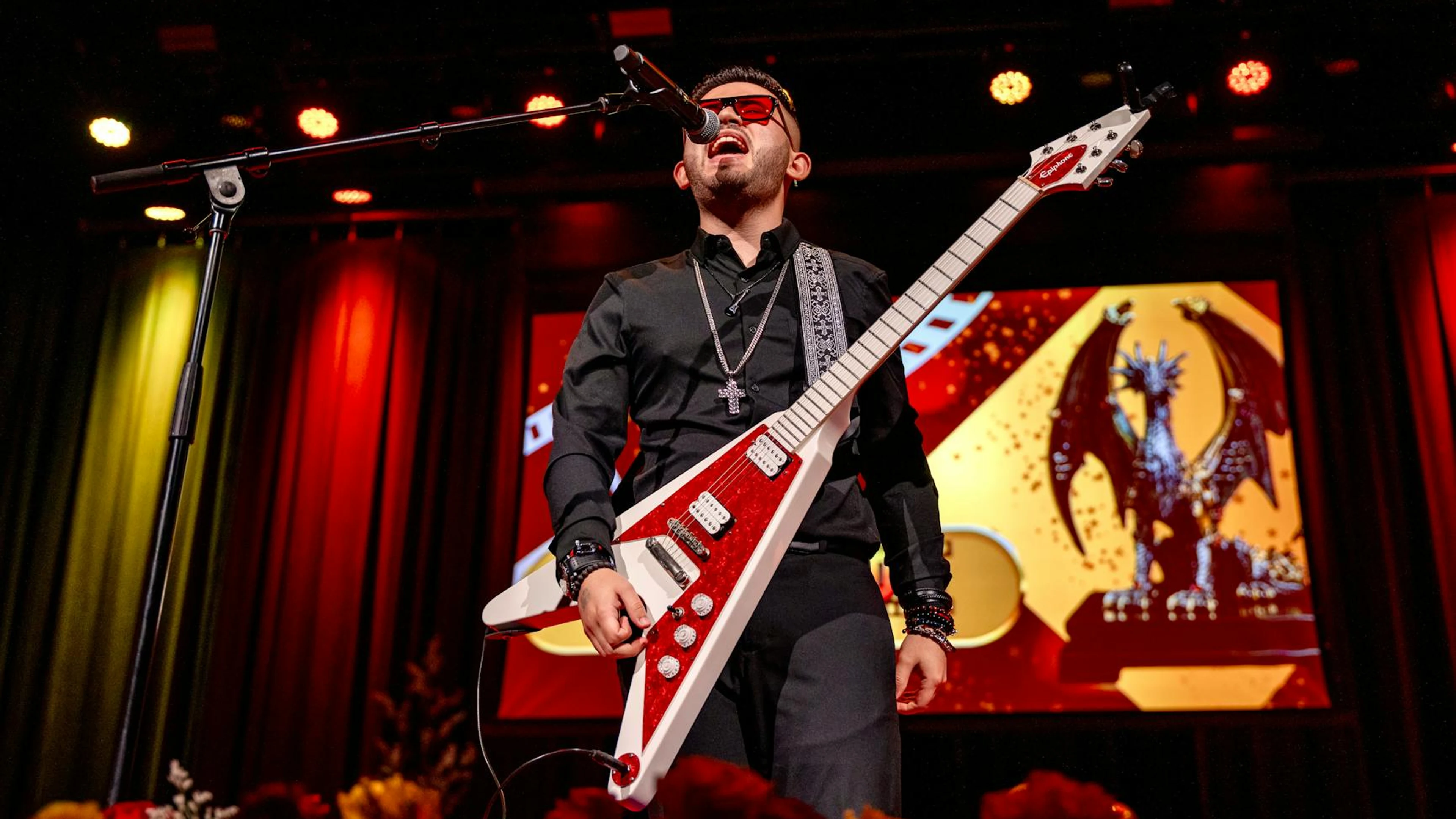 Energetic rock musician performing on stage with electric guitar and microphone - free 4K Ultra HD music wallpaper for desktop